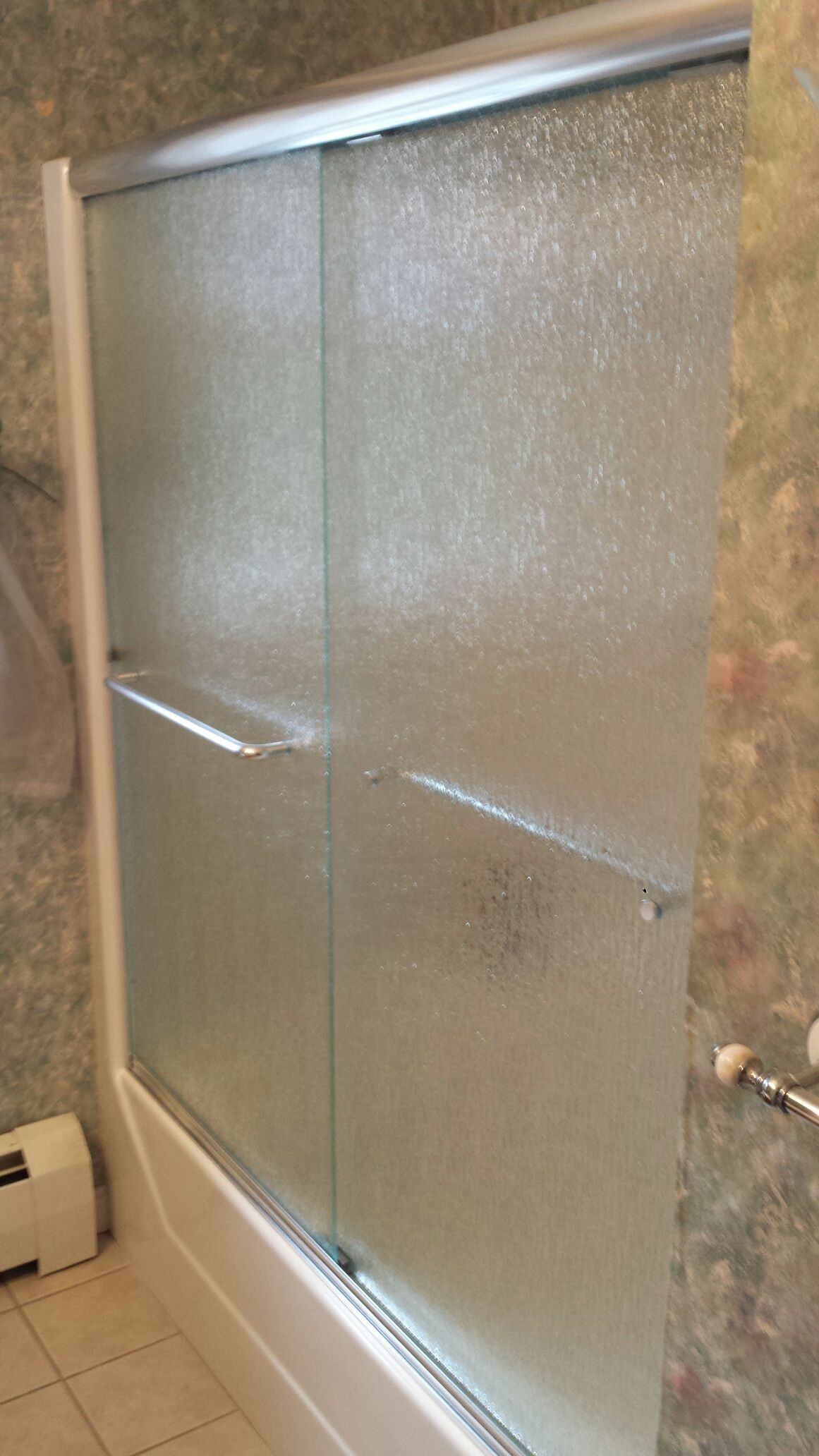 A bathroom with a sliding glass shower door and a bathtub.