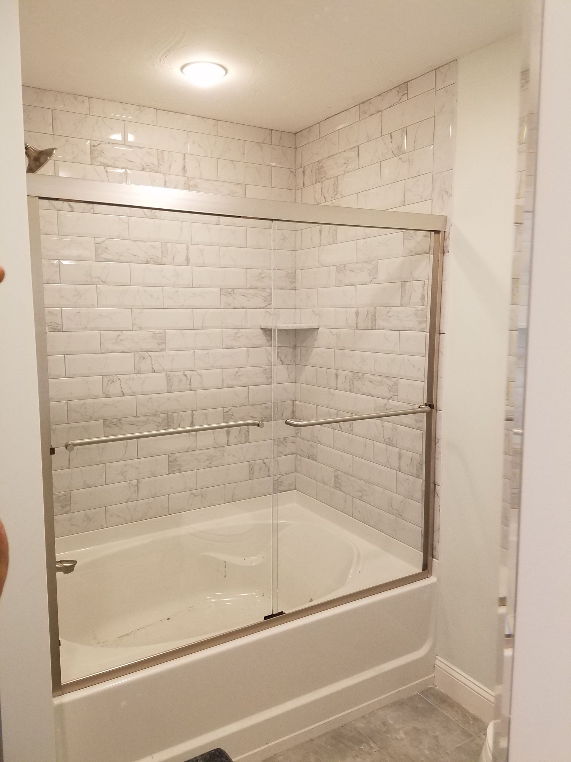 A bathroom with a bathtub and a glass shower door.