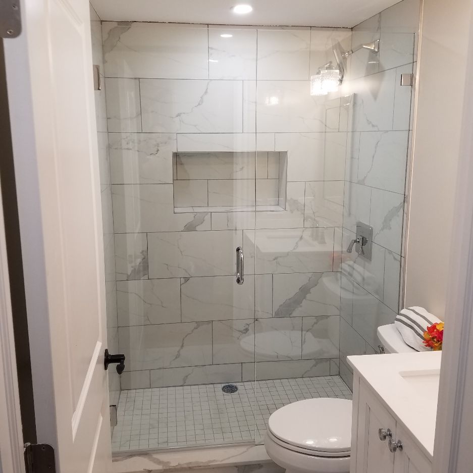 A bathroom with a toilet , sink and shower with a glass door.