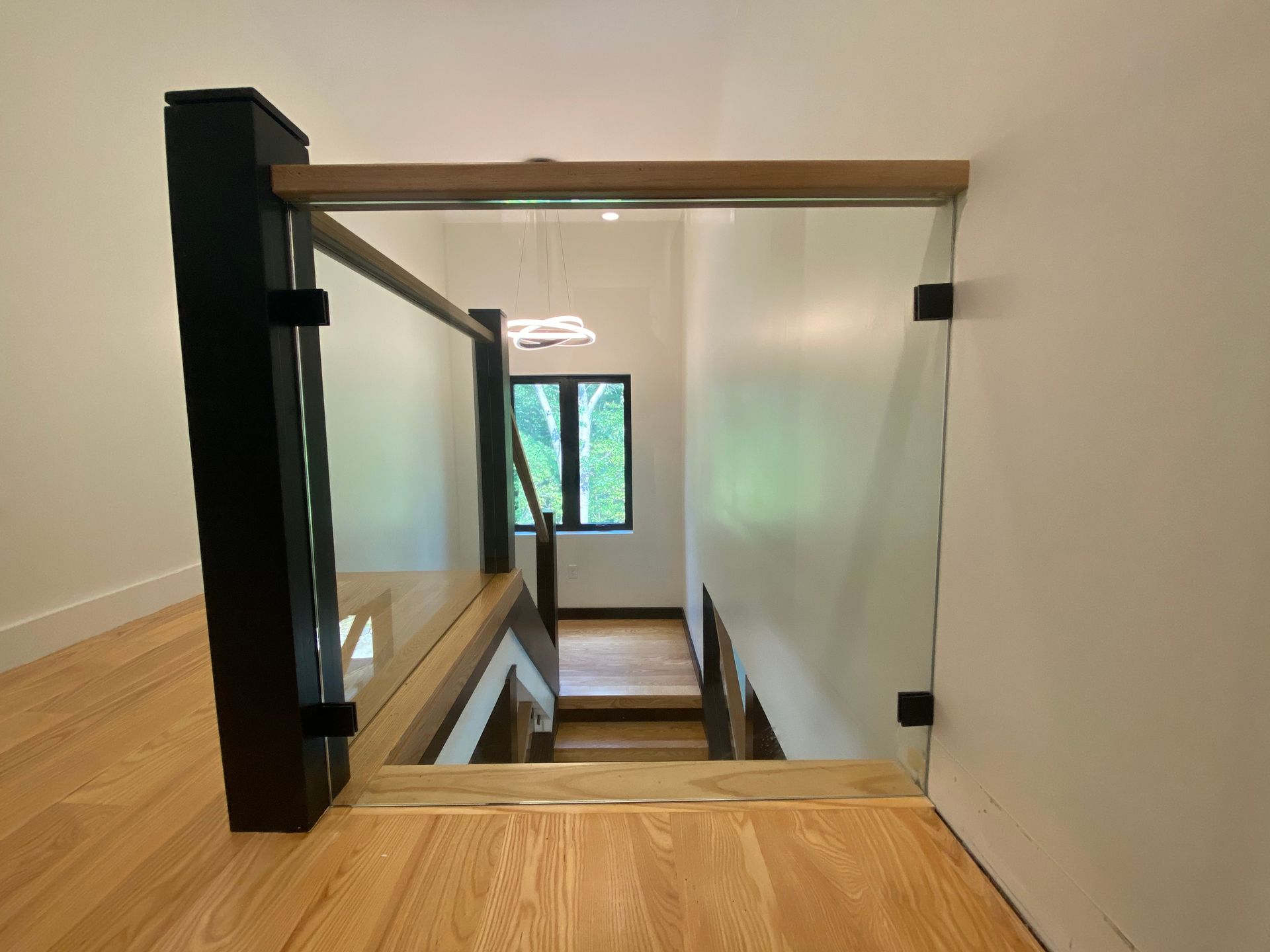 A staircase with a glass railing and a wooden handrail in a house.