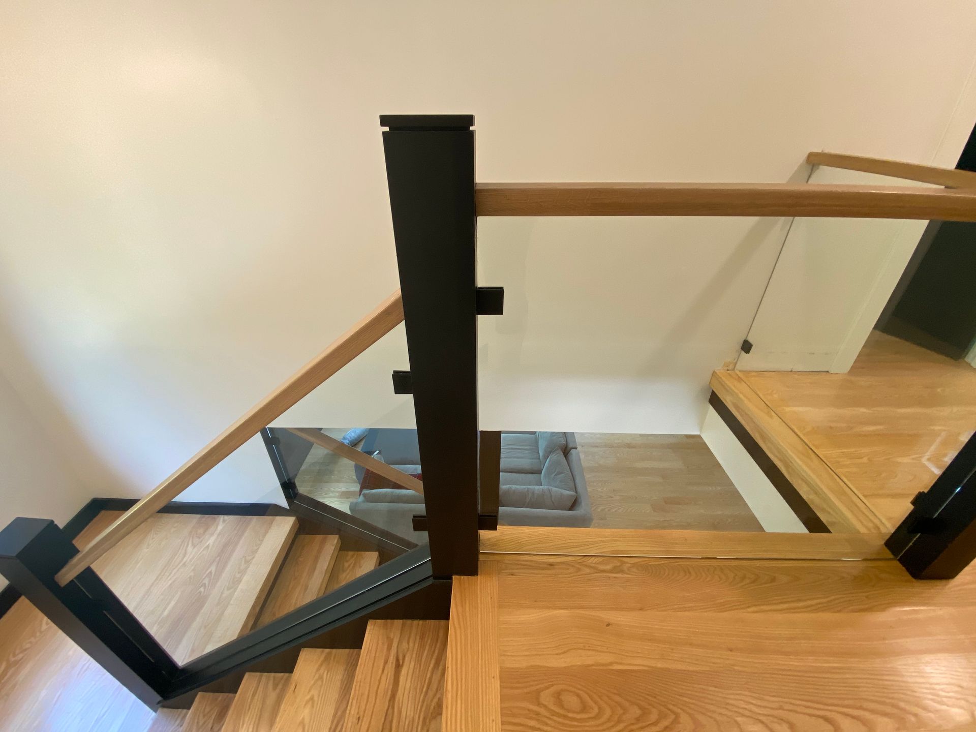 A staircase with a glass railing and wooden steps leading up to a living room.