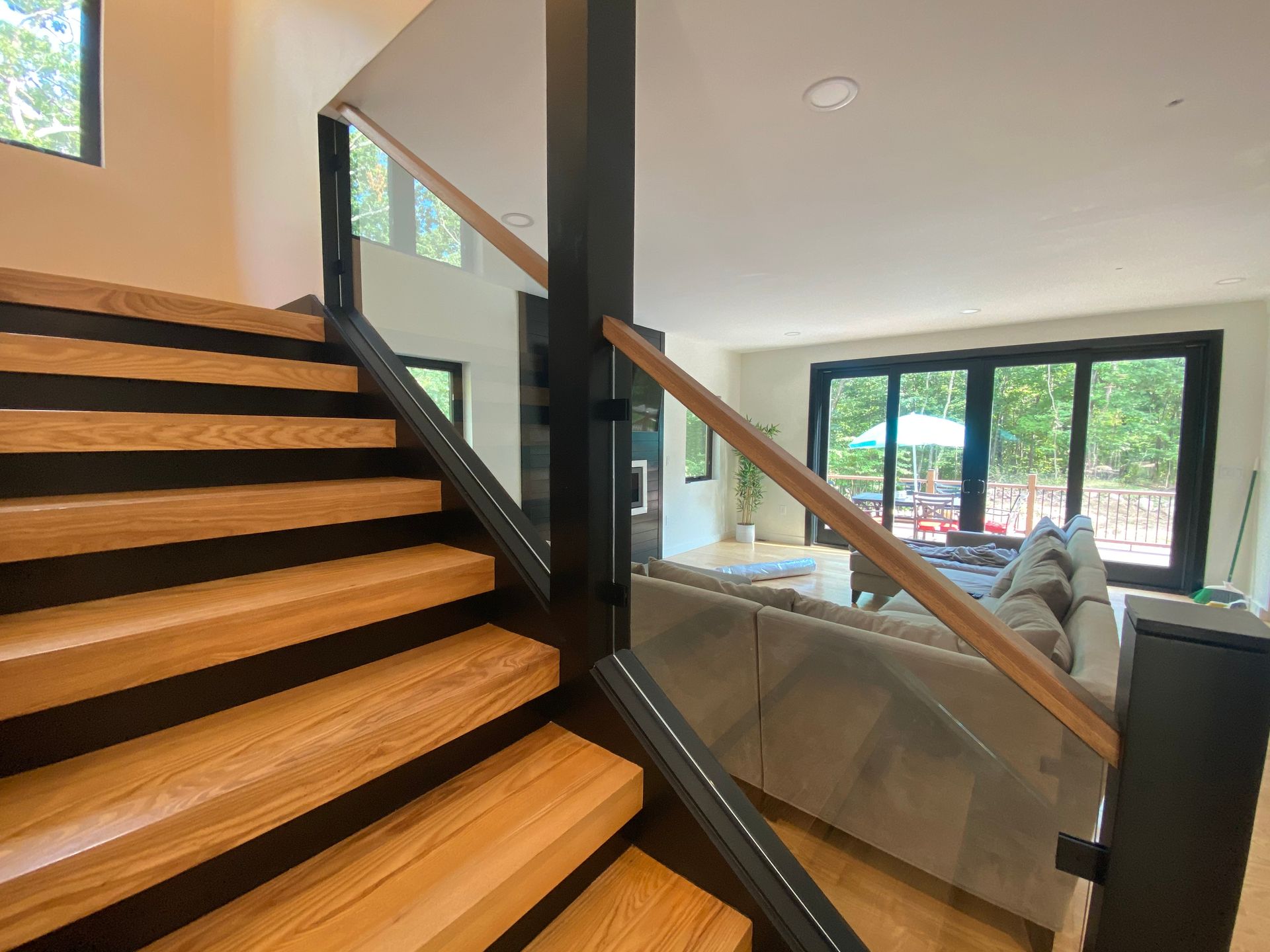 A wooden staircase with a glass railing in a living room.