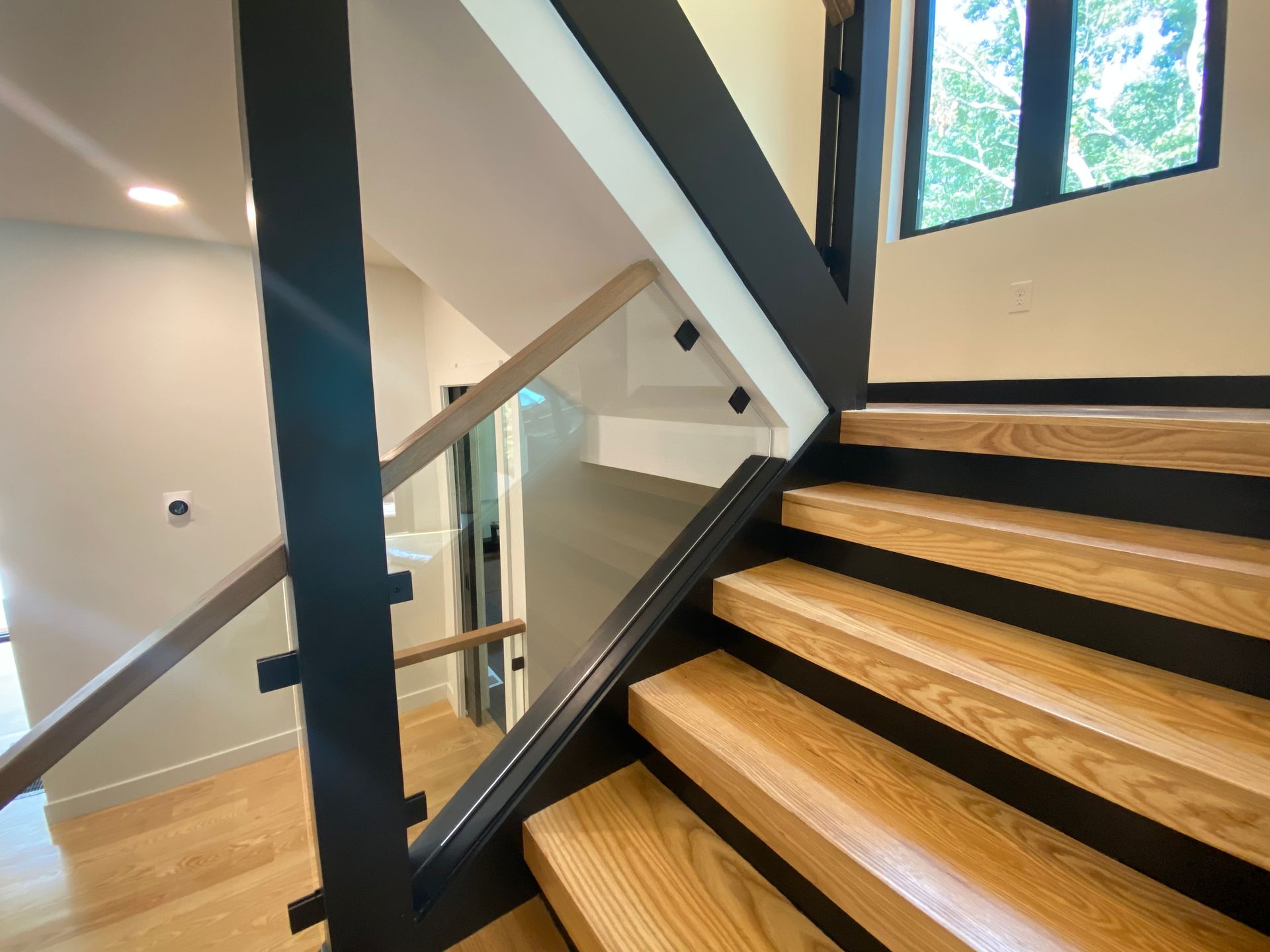 The stairs are made of wood and metal and have a glass railing.