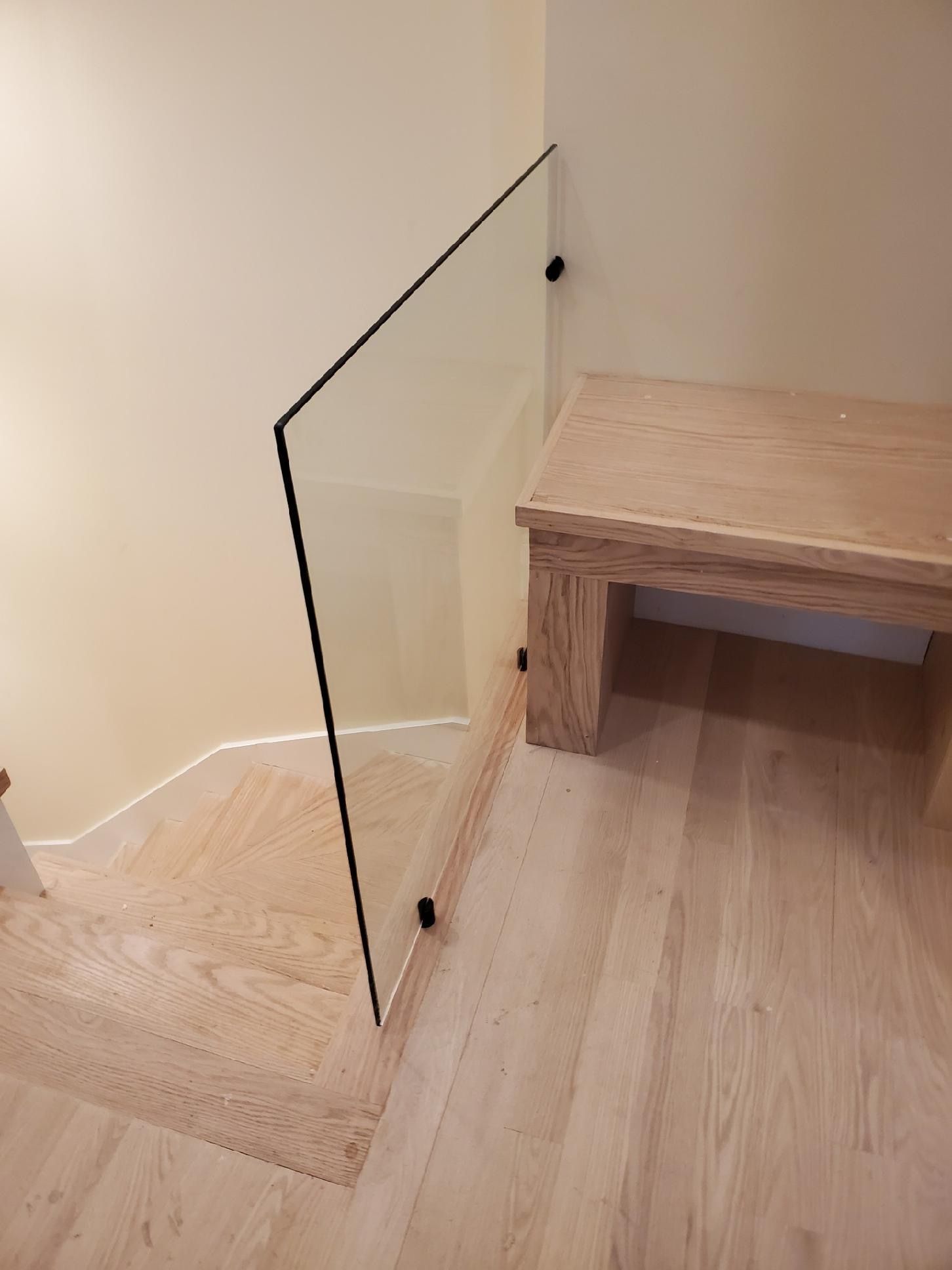 A staircase with a glass railing and a wooden bench