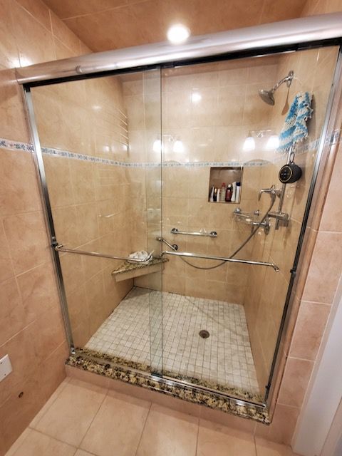 A bathroom with a walk in shower with a glass door