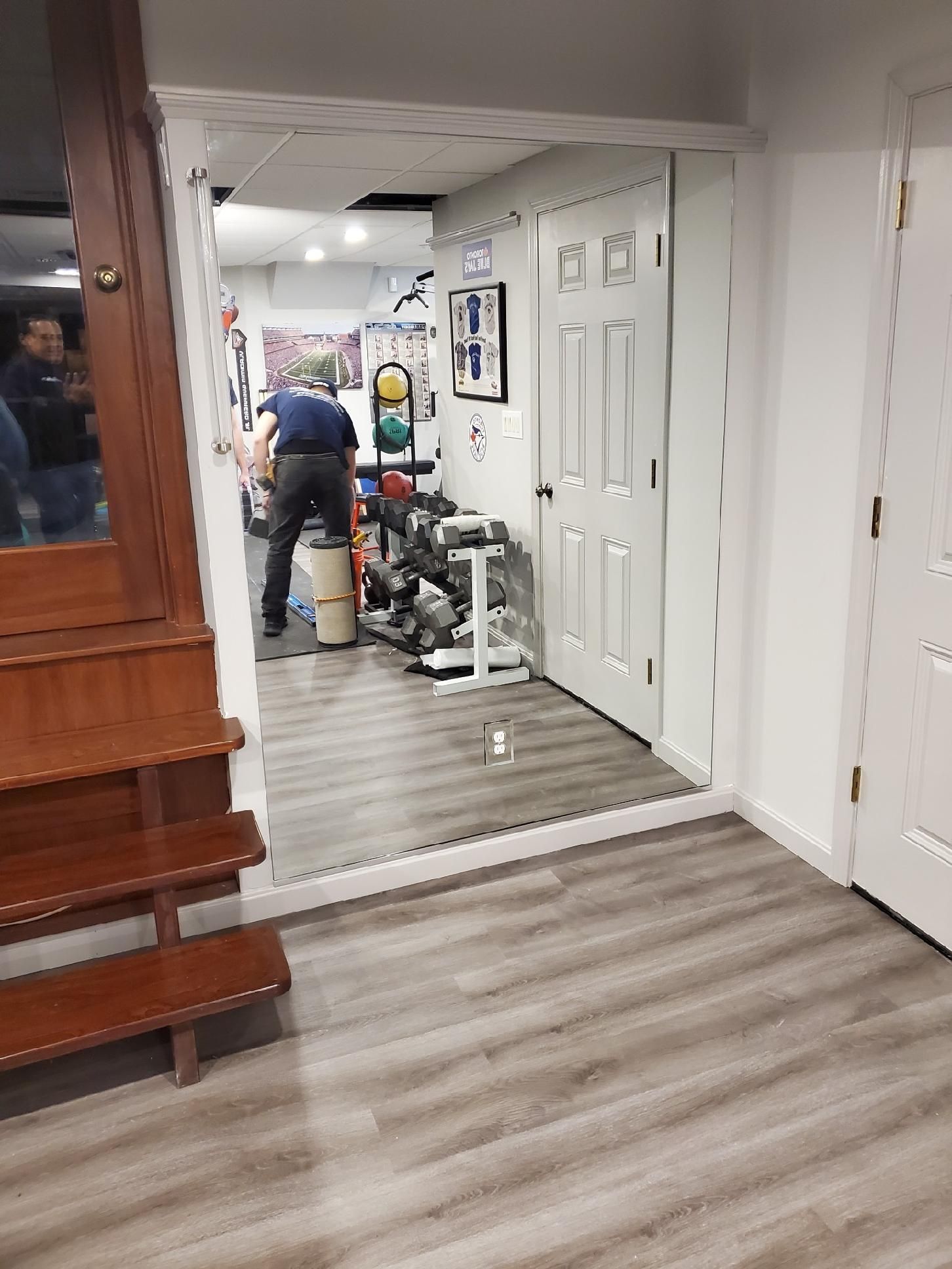 A man is standing in a room with a large mirror.