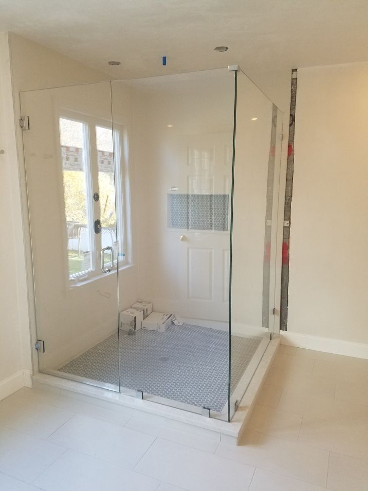 A bathroom with a walk in shower and a window.