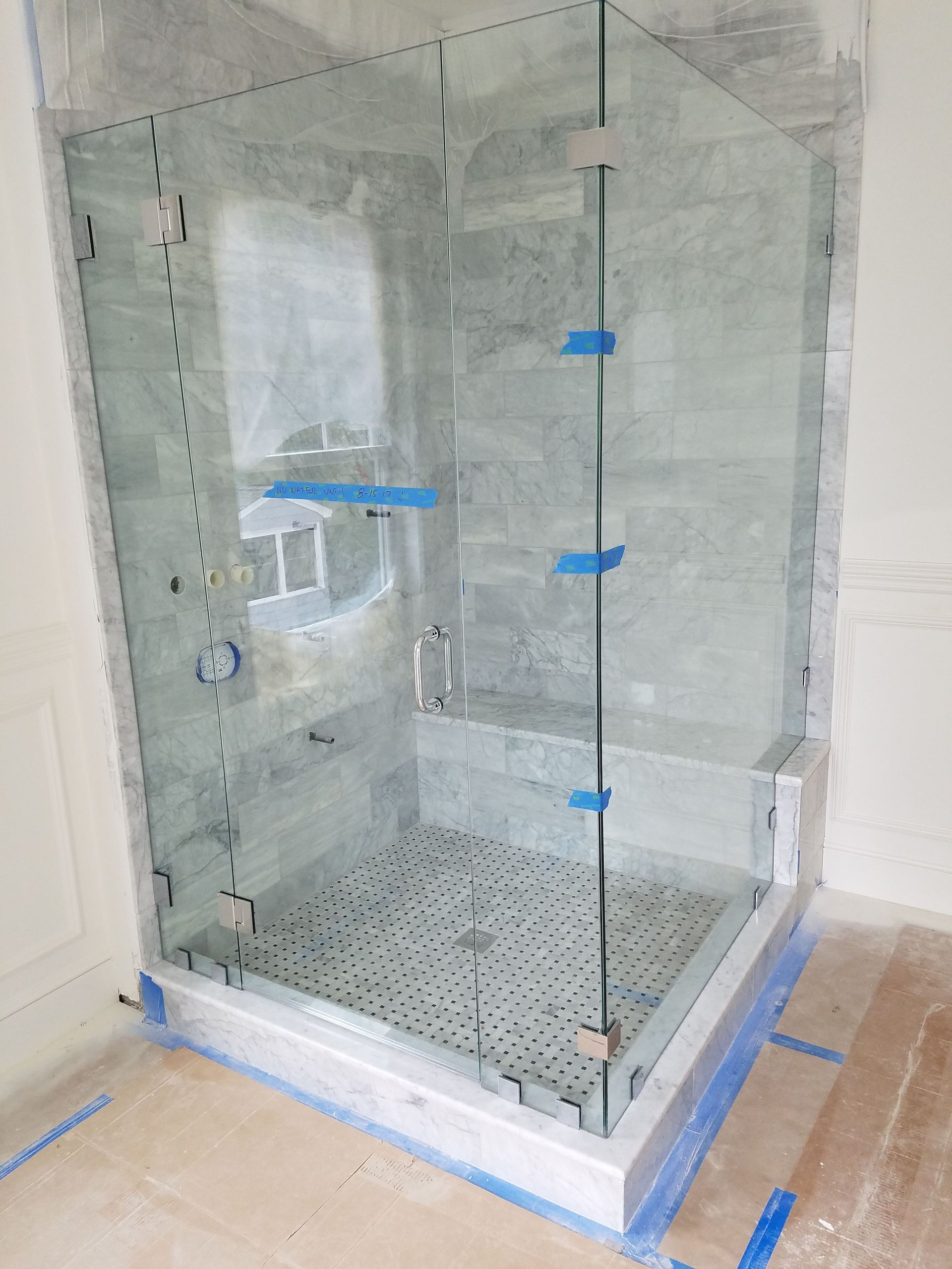 A shower stall with a glass door is being built in a bathroom.