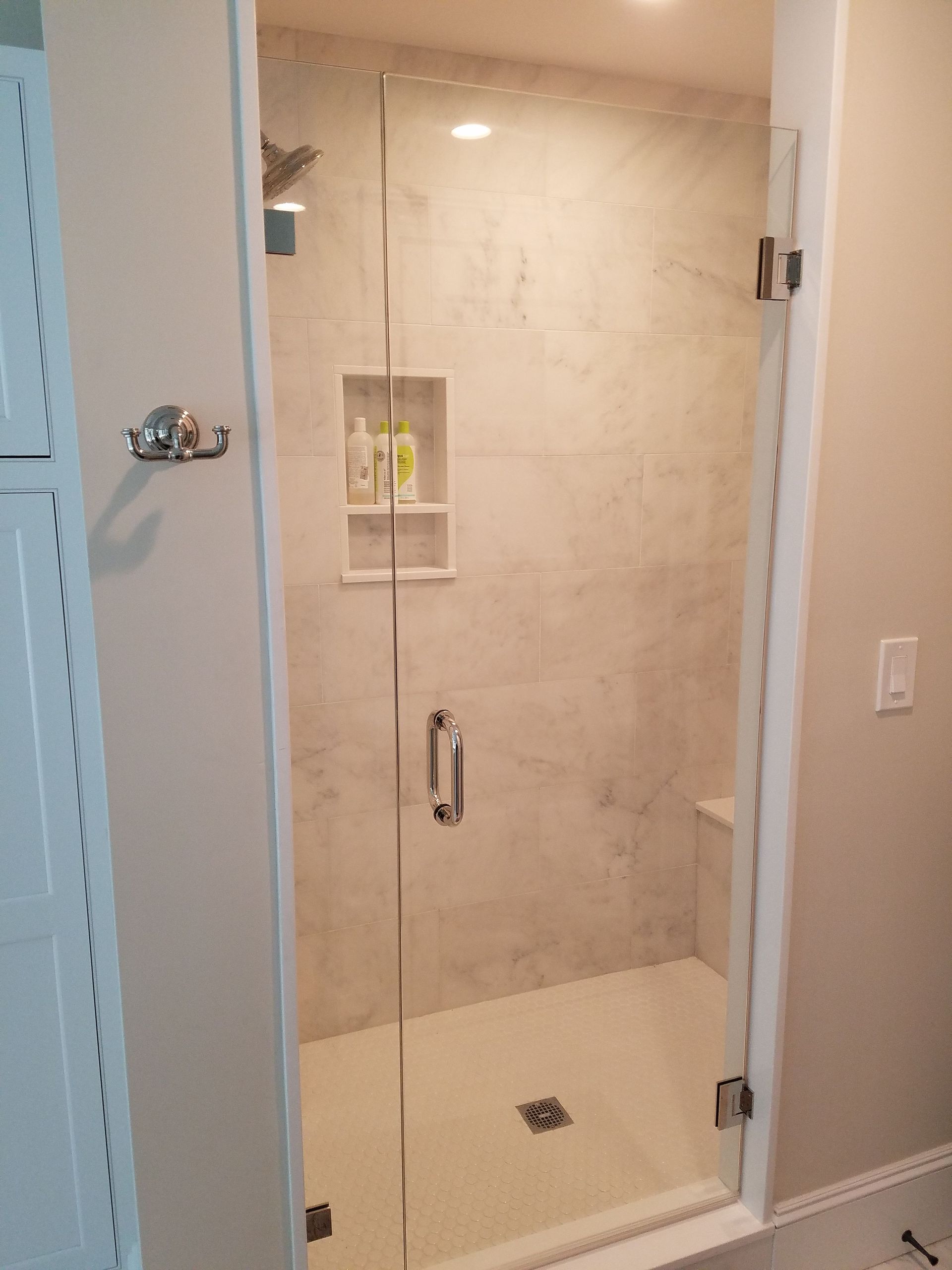 A bathroom with a walk in shower with a glass door.