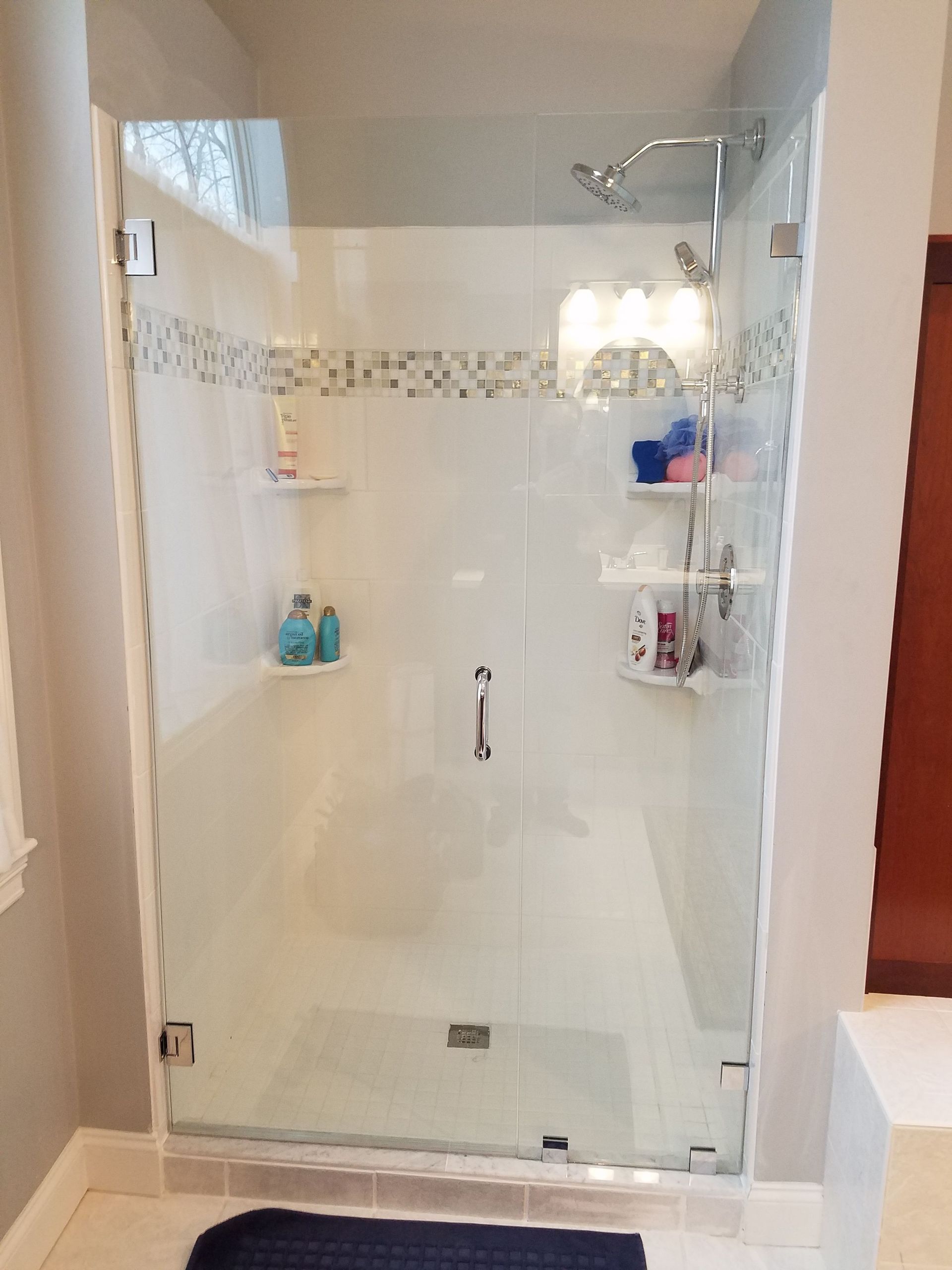 A bathroom with a walk in shower with a glass door