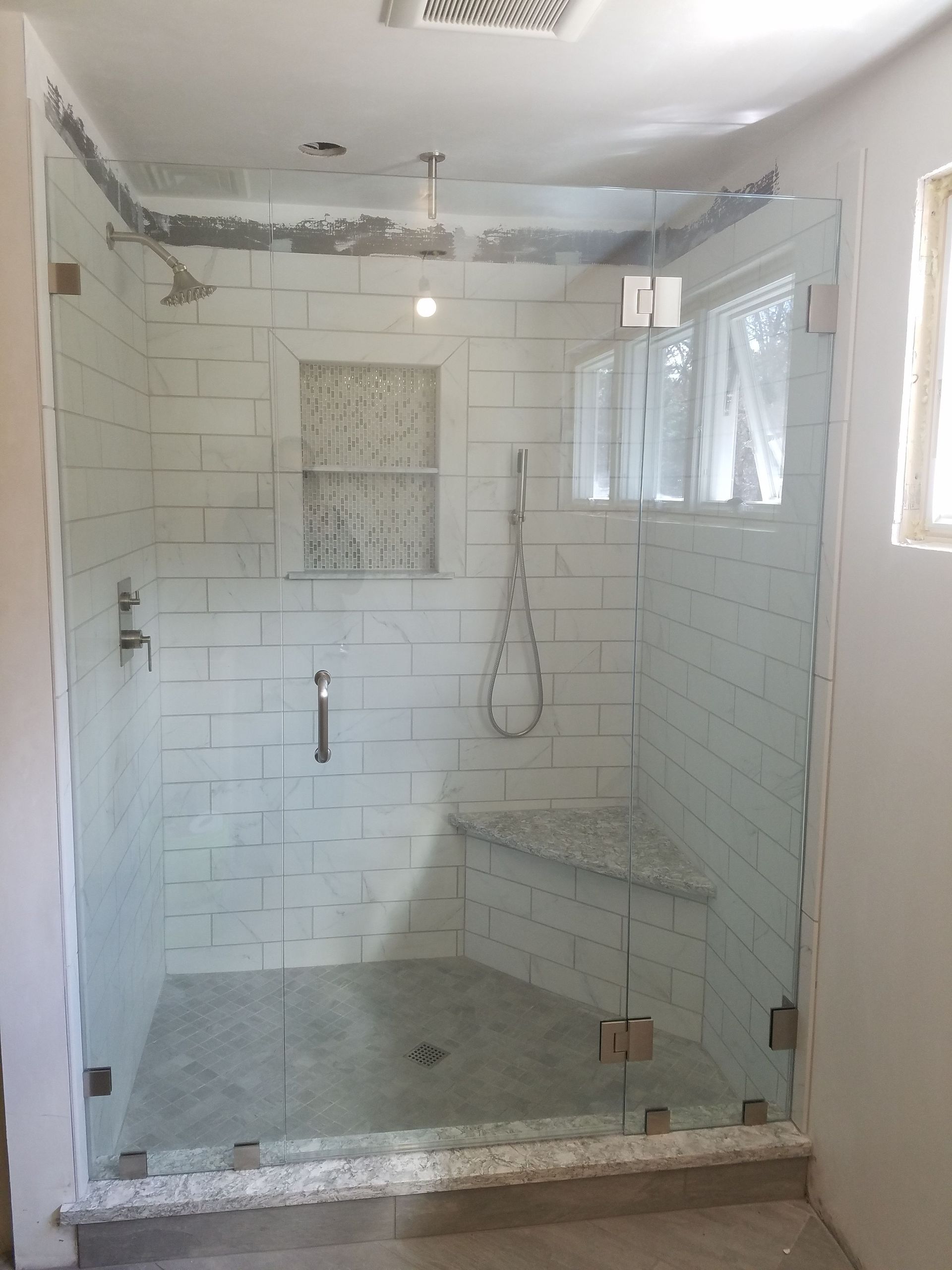 A bathroom with a walk in shower with a glass door.