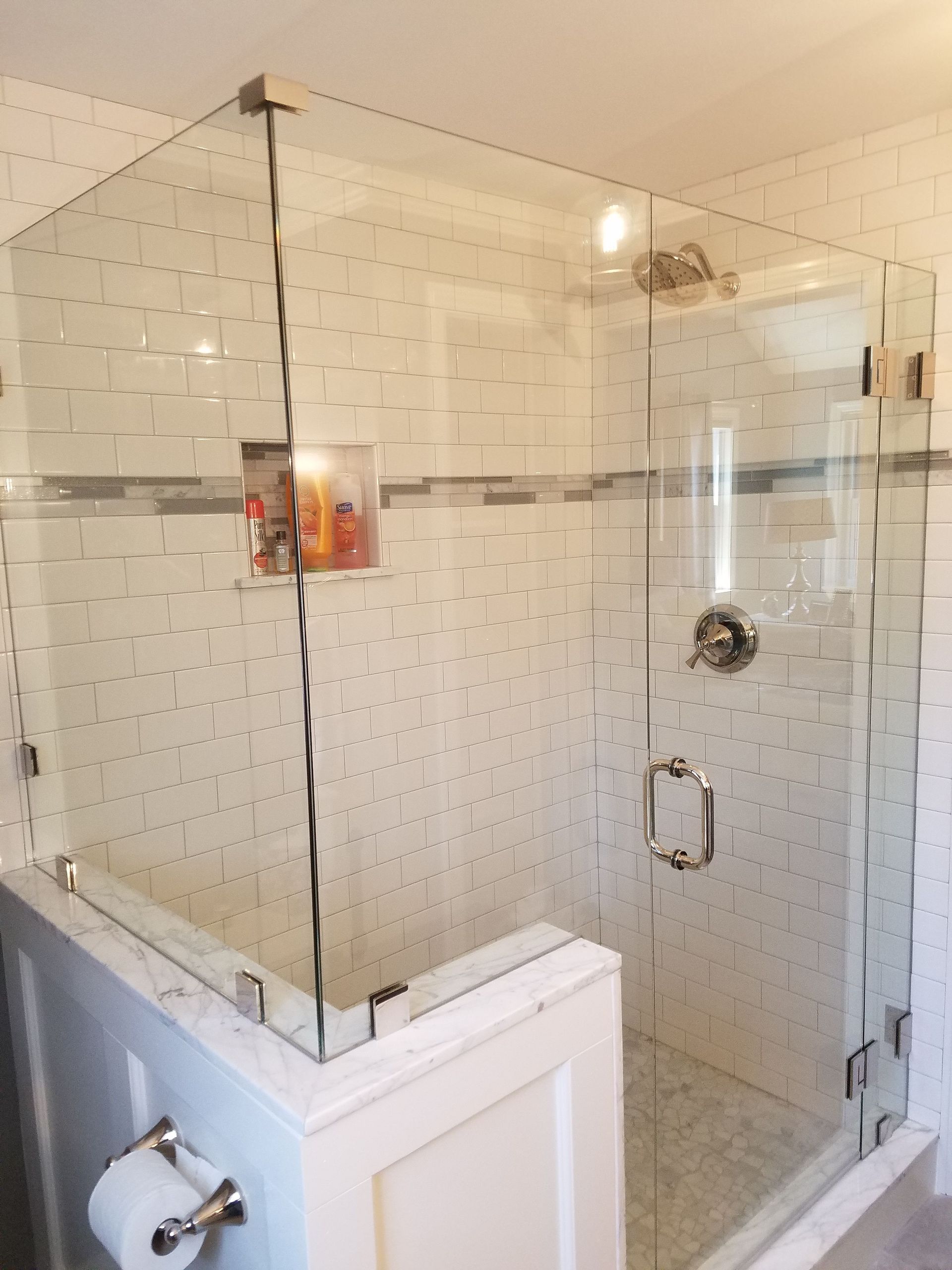 A bathroom with a walk in shower with a glass door.