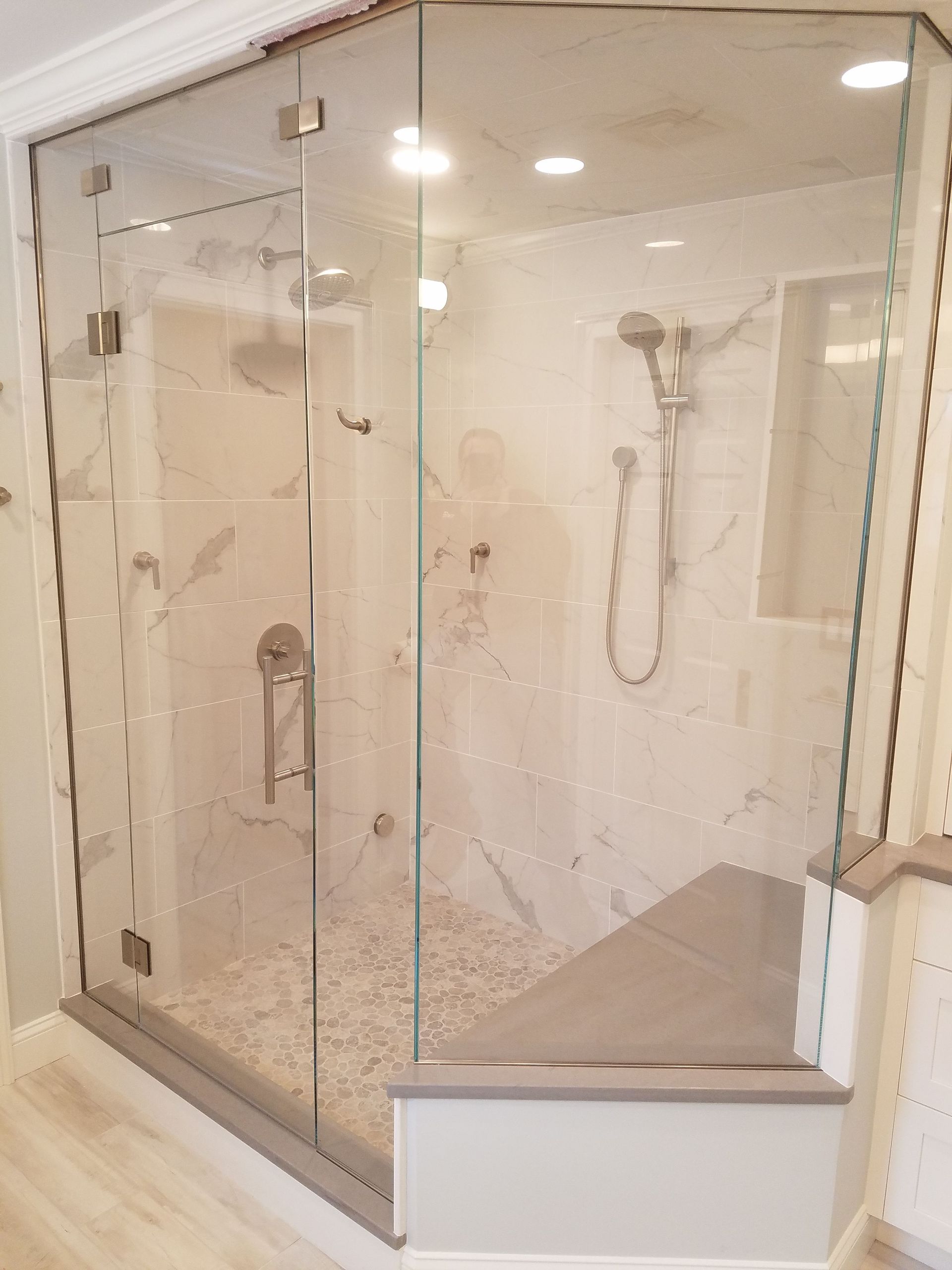 A bathroom with a walk in shower with a glass door.