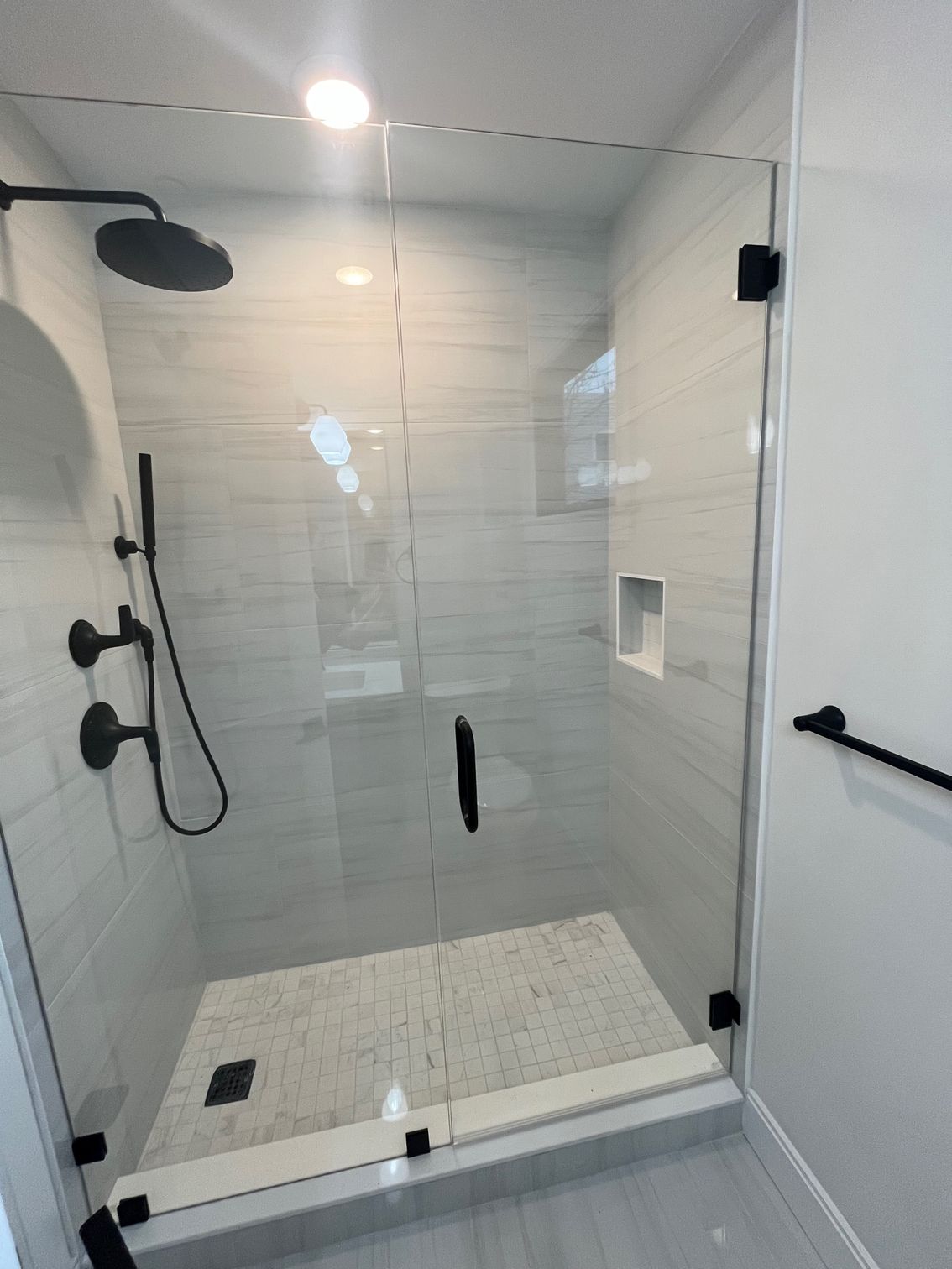 A bathroom with a walk in shower with a glass door and a shower head.