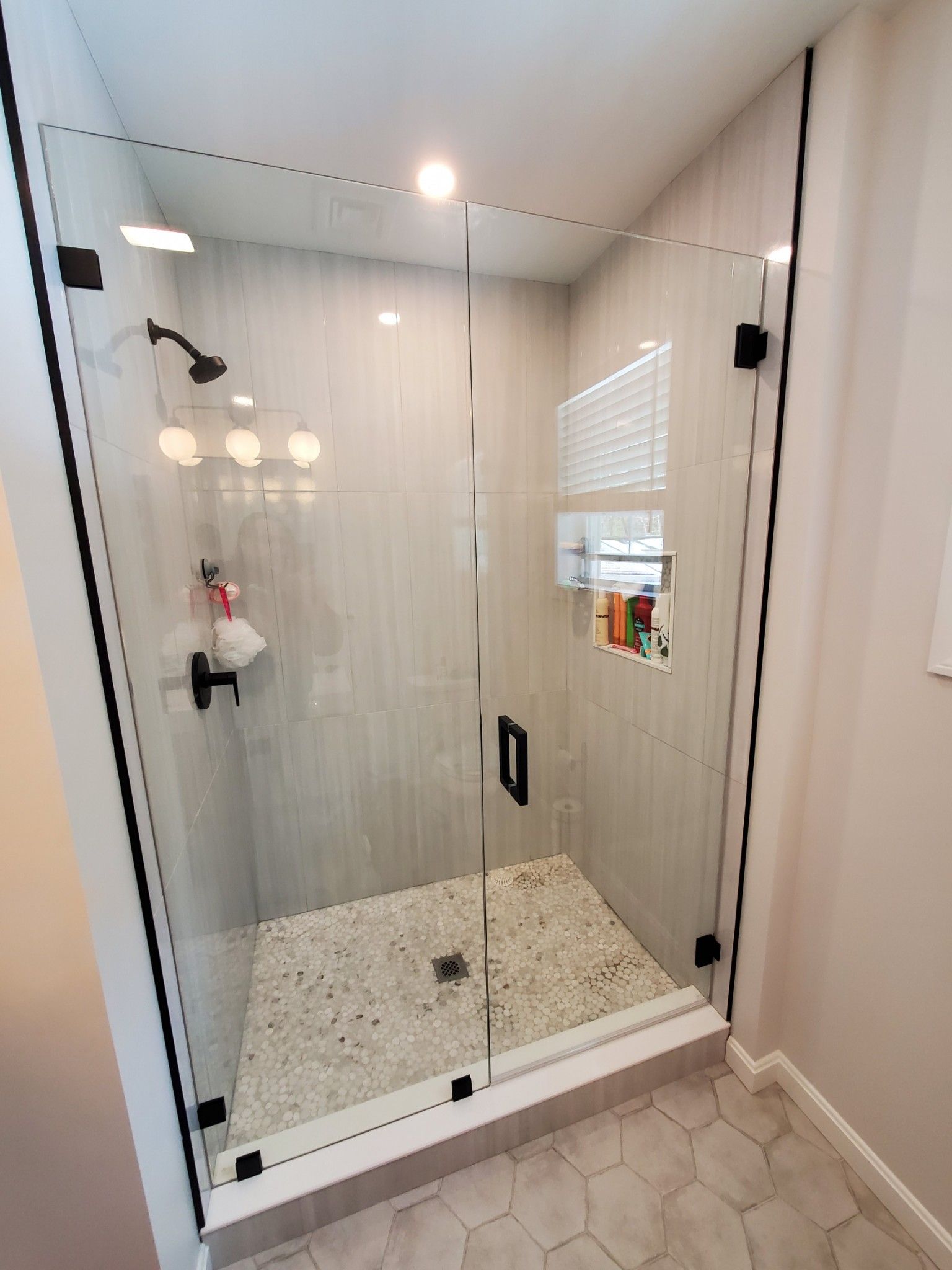 A bathroom with a walk in shower with a glass door.