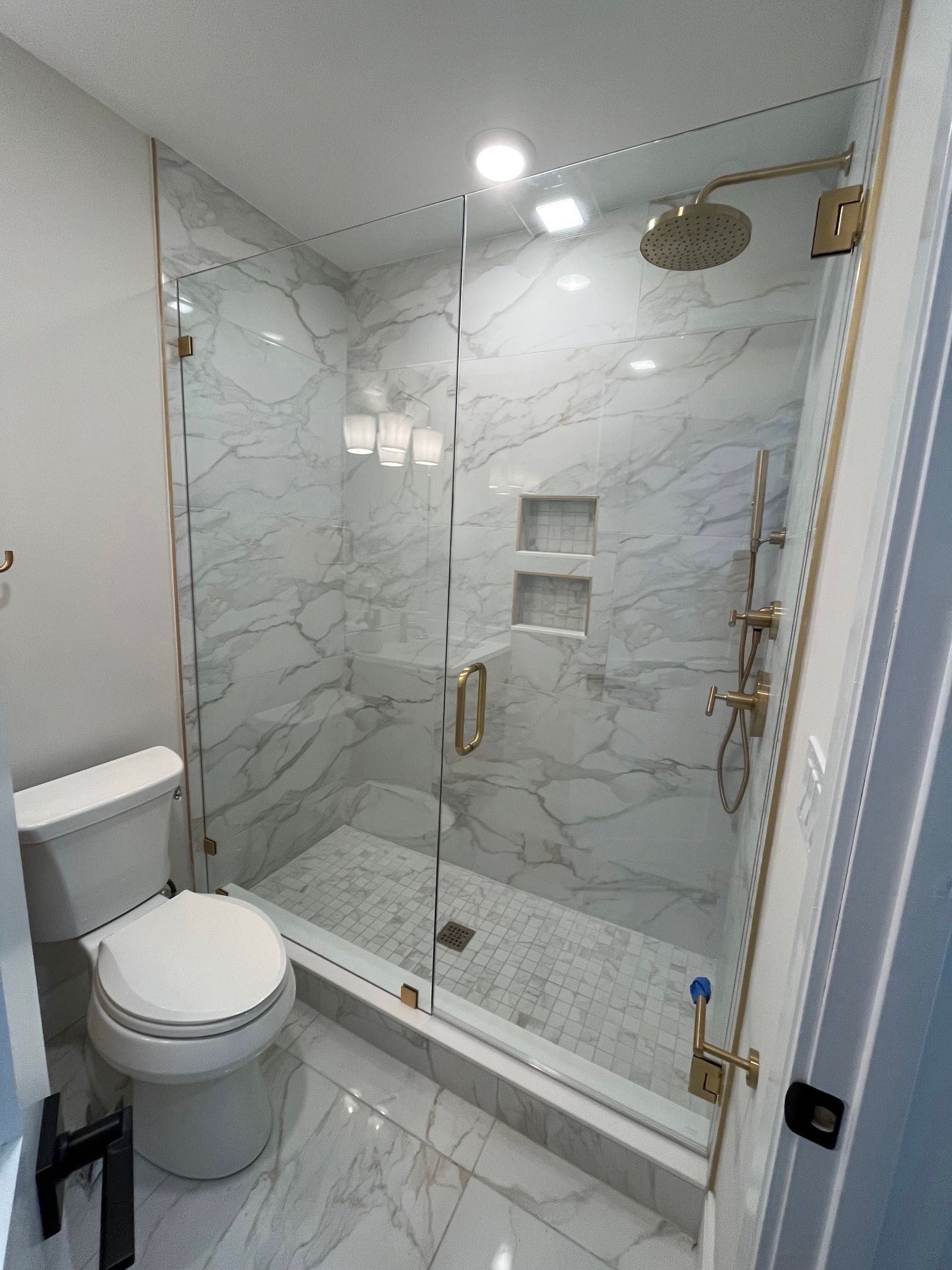 A bathroom with a toilet and a walk in shower with a glass door.