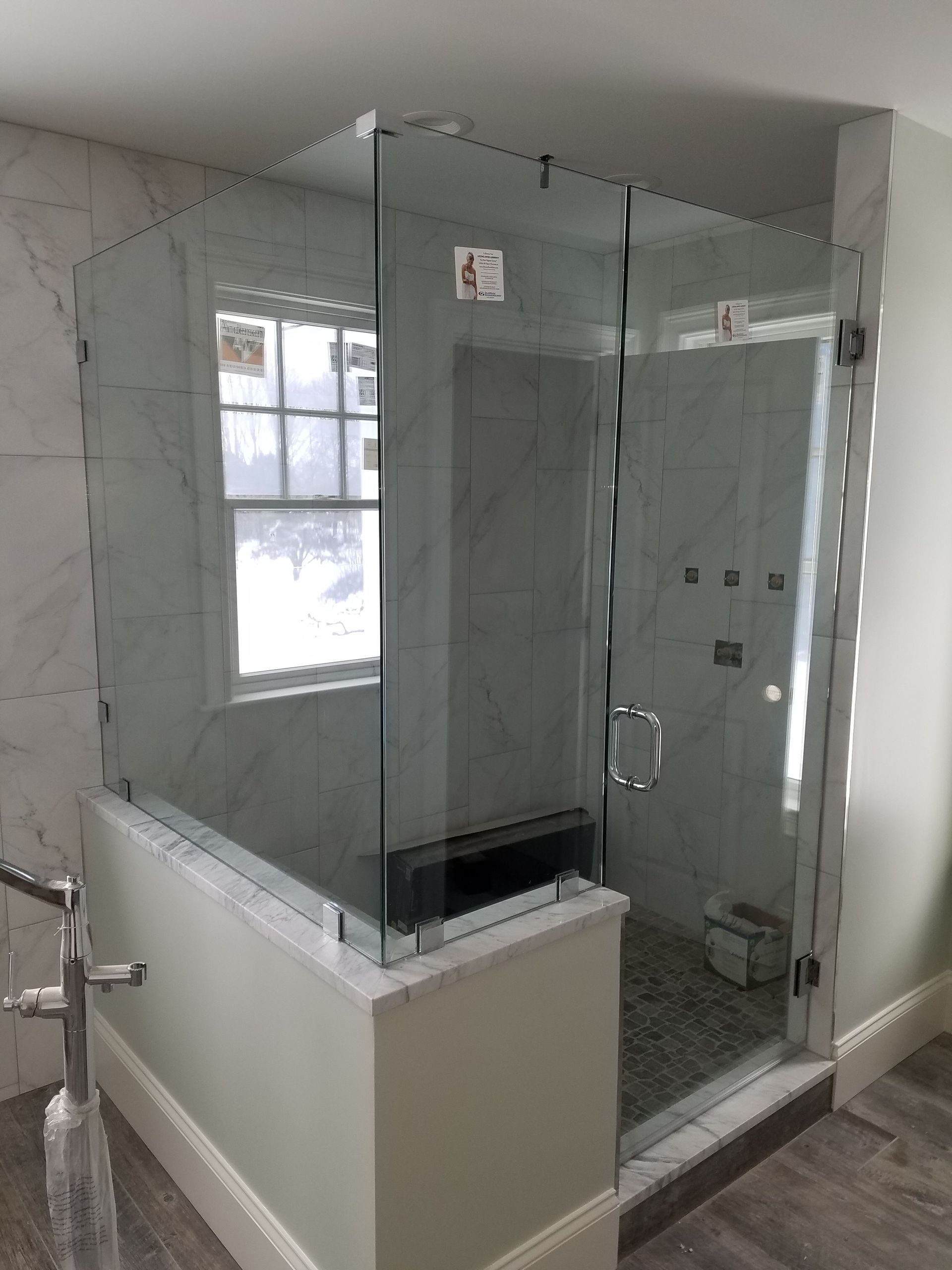 A bathroom with a glass shower door and a window.