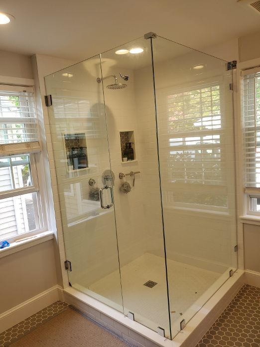 A bathroom with a walk in shower and a window.