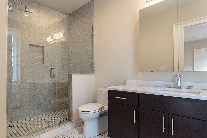 A bathroom with a toilet , sink and walk in shower.