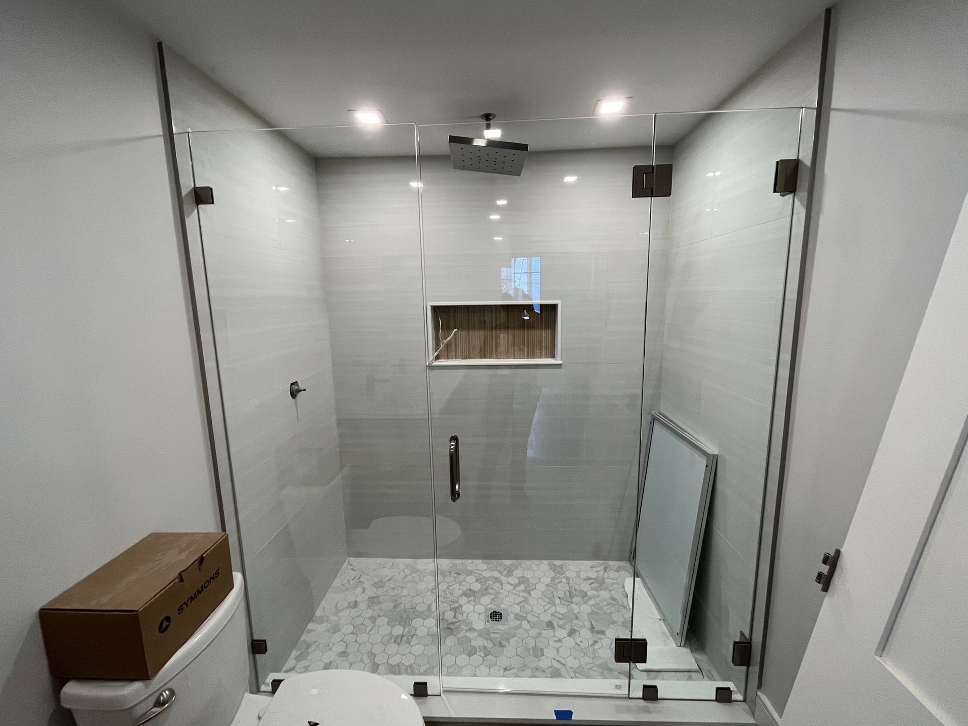 A bathroom with a glass shower door and a toilet.