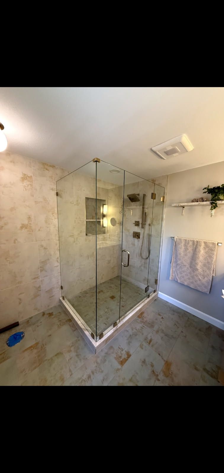 A bathroom with a walk in shower with a glass door.