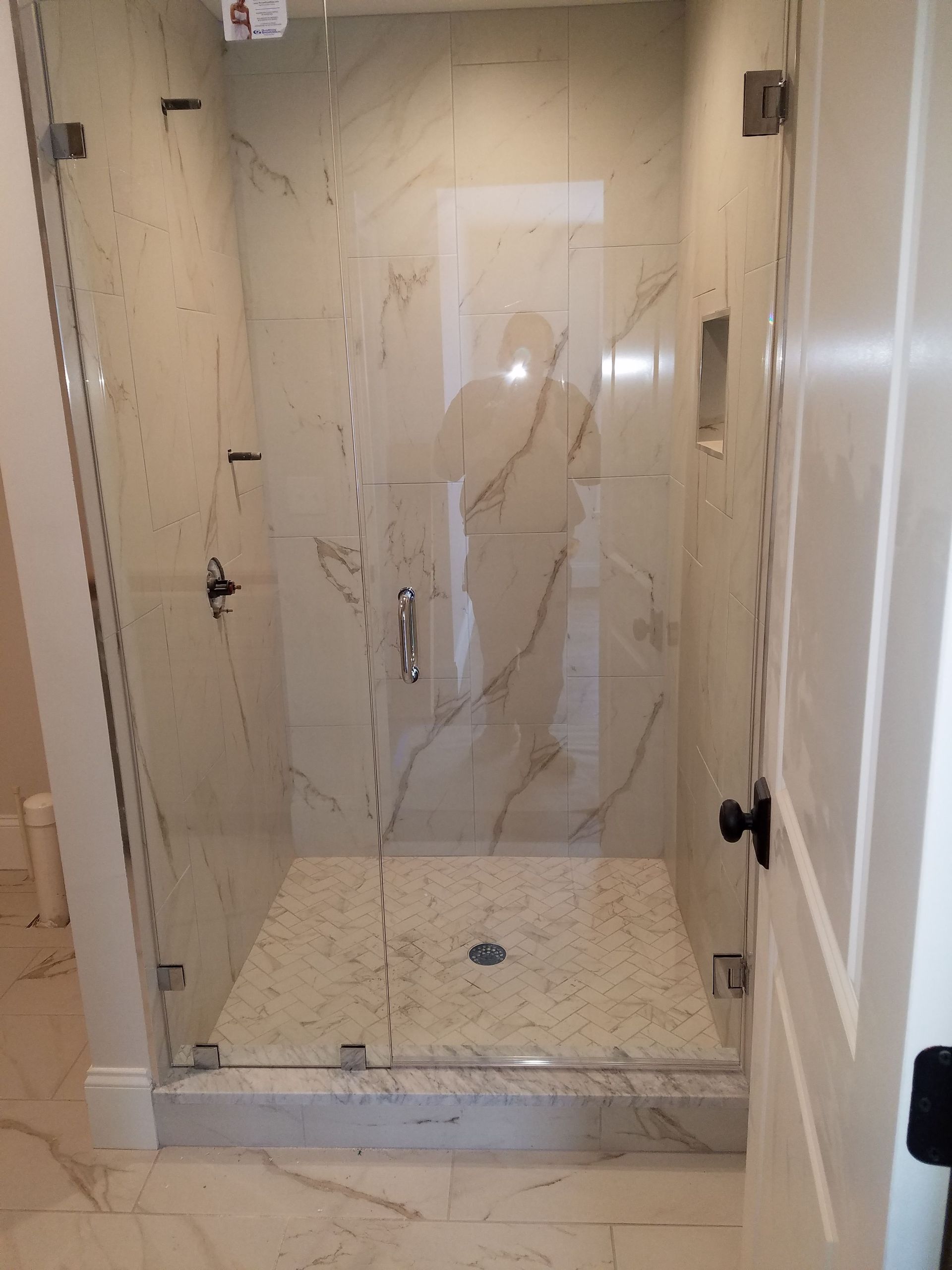 A bathroom with a walk in shower with a glass door.