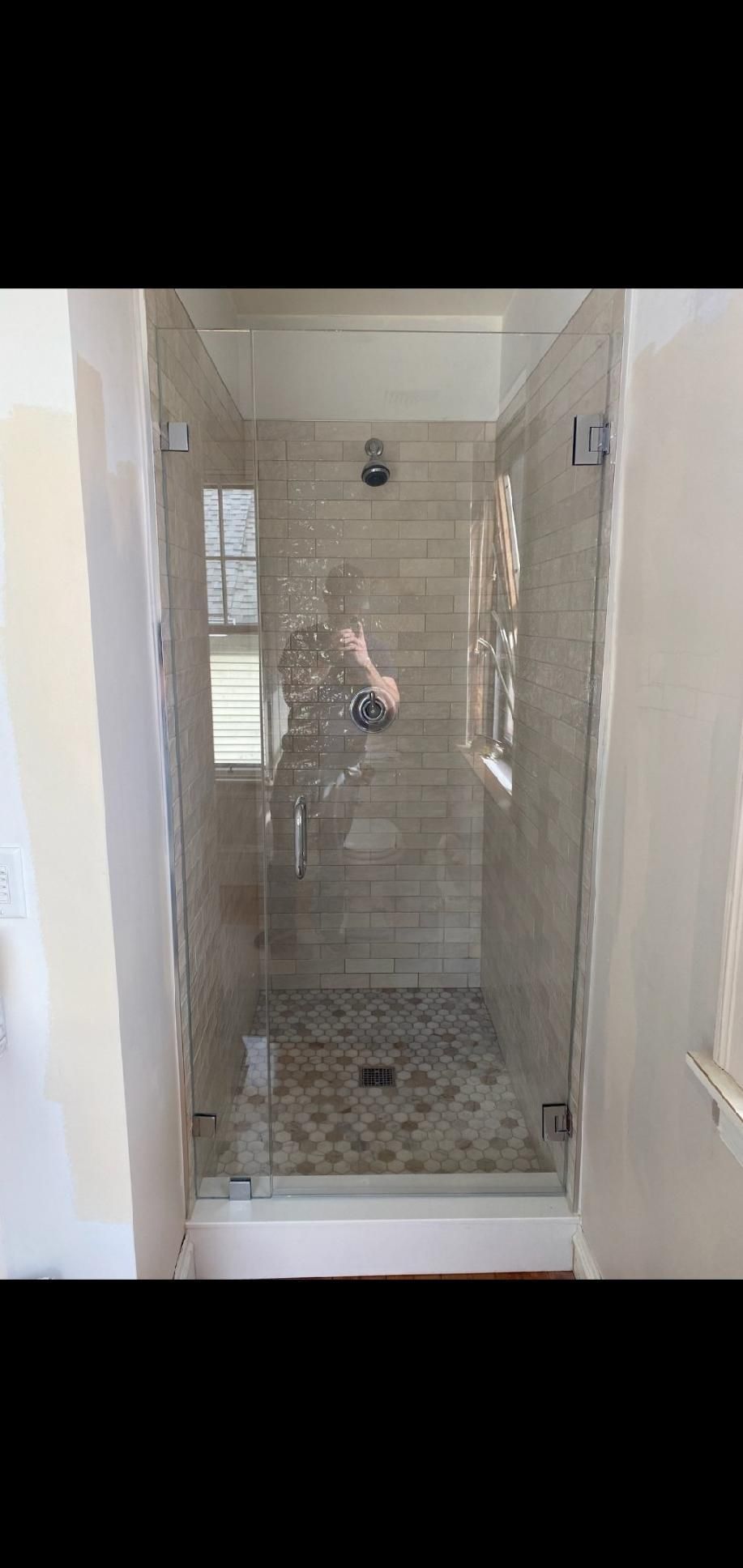 A bathroom with a walk in shower with a glass door.