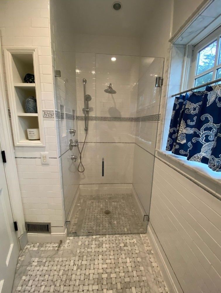 A bathroom with a walk in shower and a window.