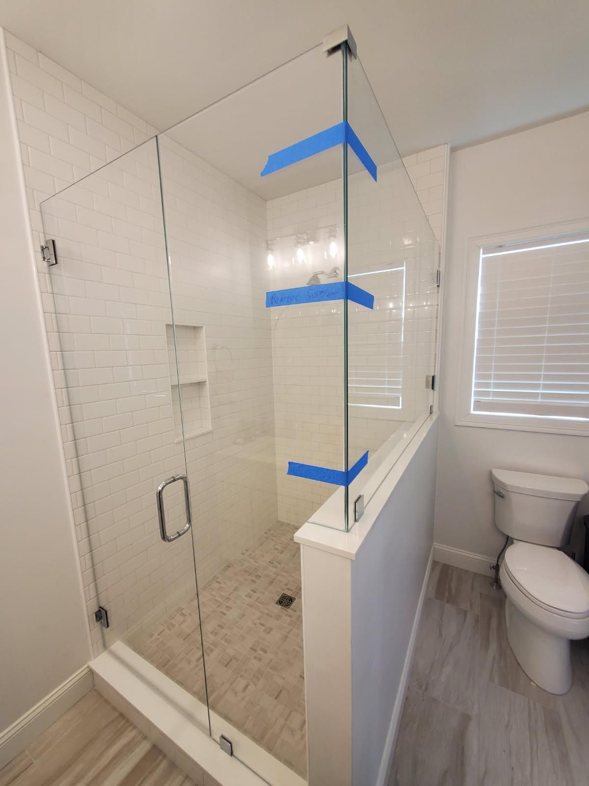 A bathroom with a glass shower door and a toilet.