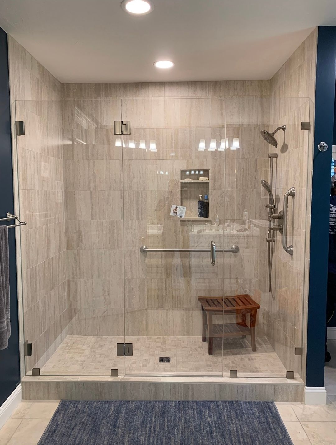 A bathroom with a walk in shower with a glass door.