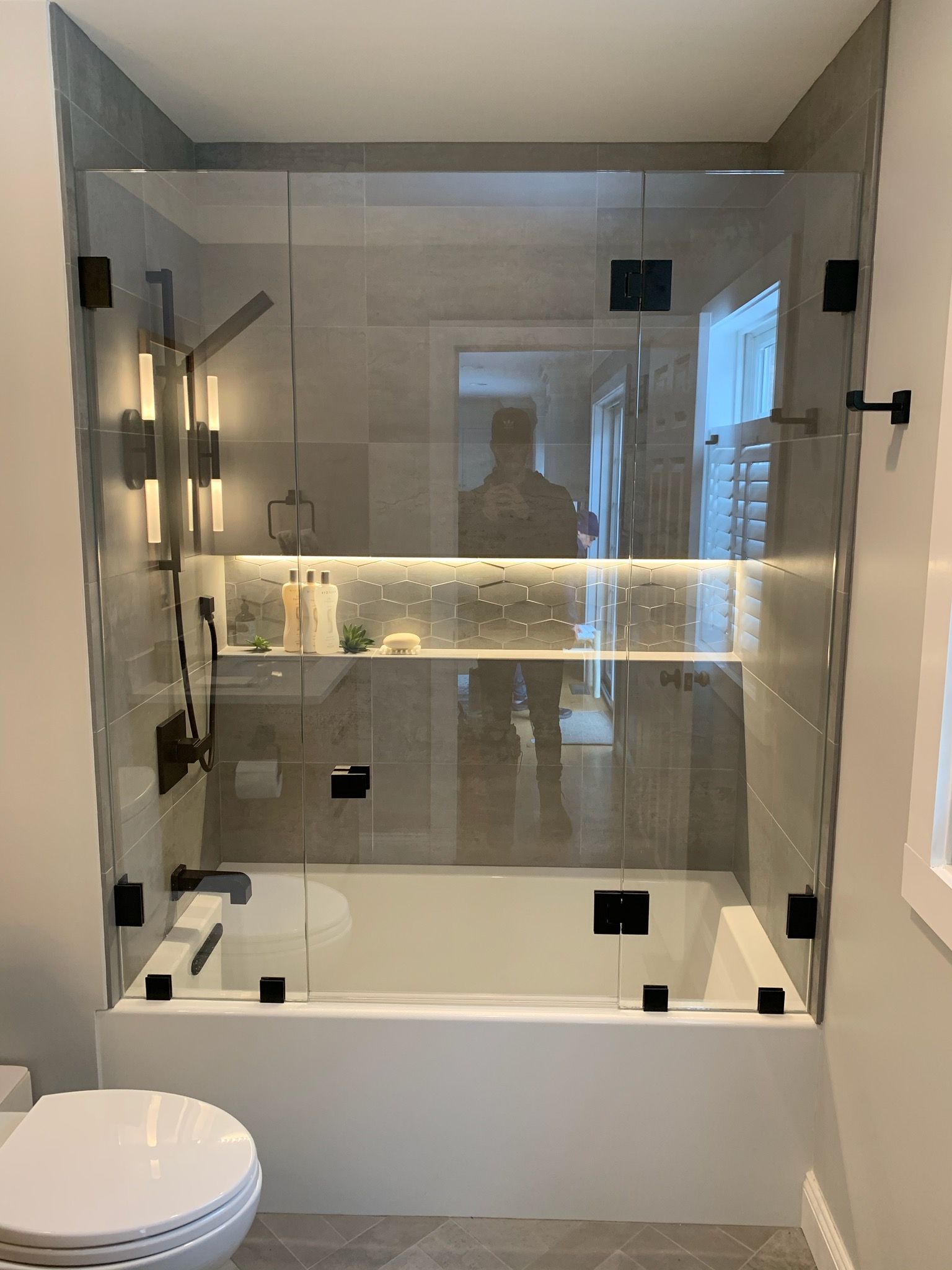 A bathroom with a bathtub , toilet and shower with a glass door.