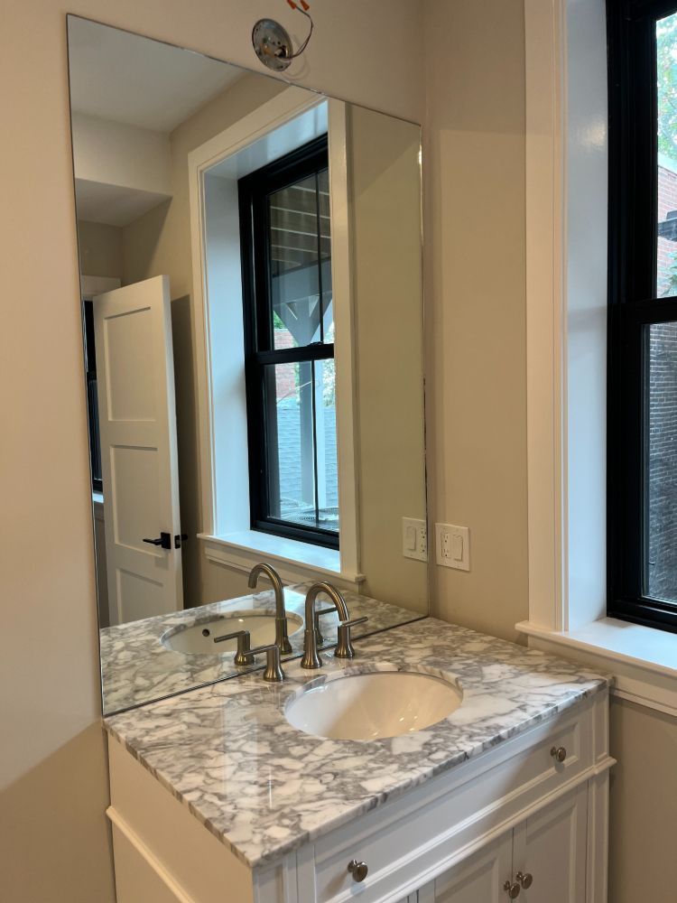 A bathroom with a sink , mirror and window