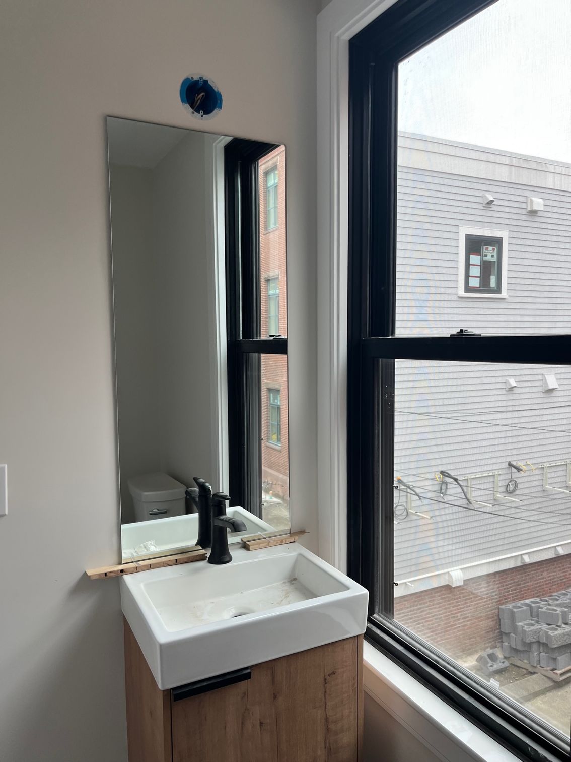 A bathroom with a sink , mirror and window.
