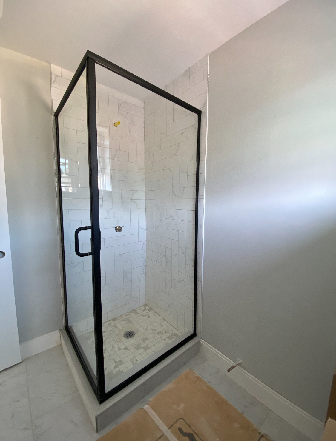 A bathroom with a shower stall with a black frame.