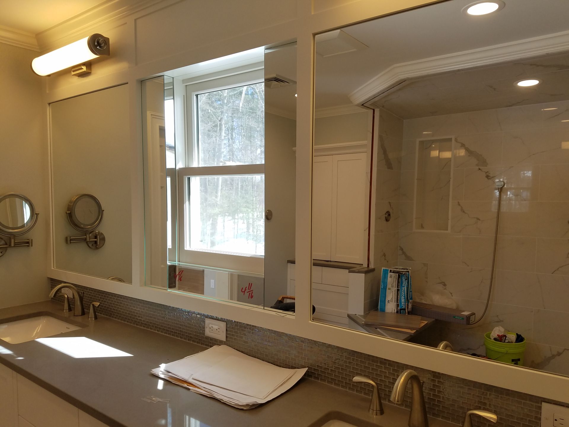 A bathroom with two sinks , two mirrors and a window.