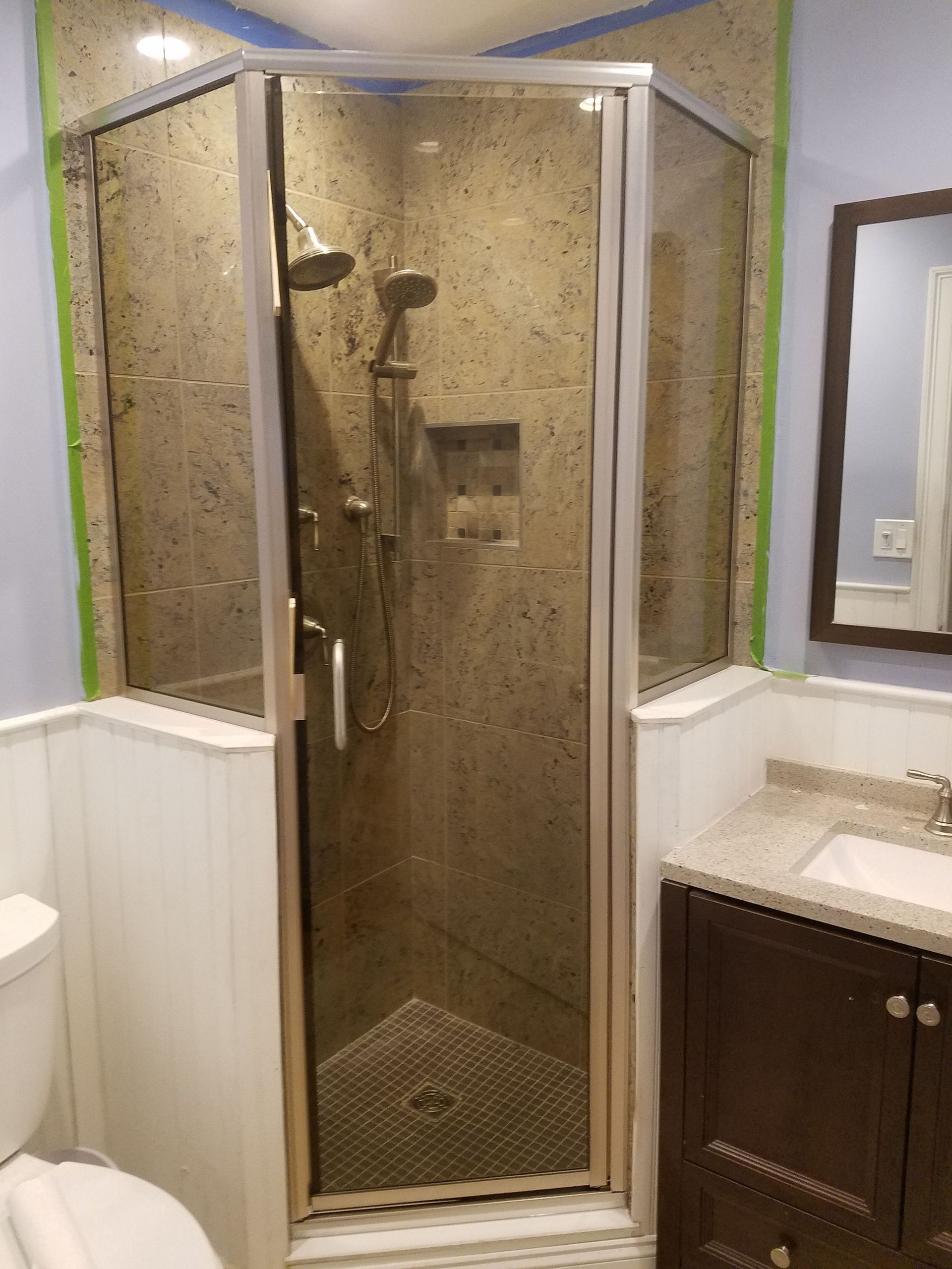 A bathroom with a shower , toilet , sink and mirror.