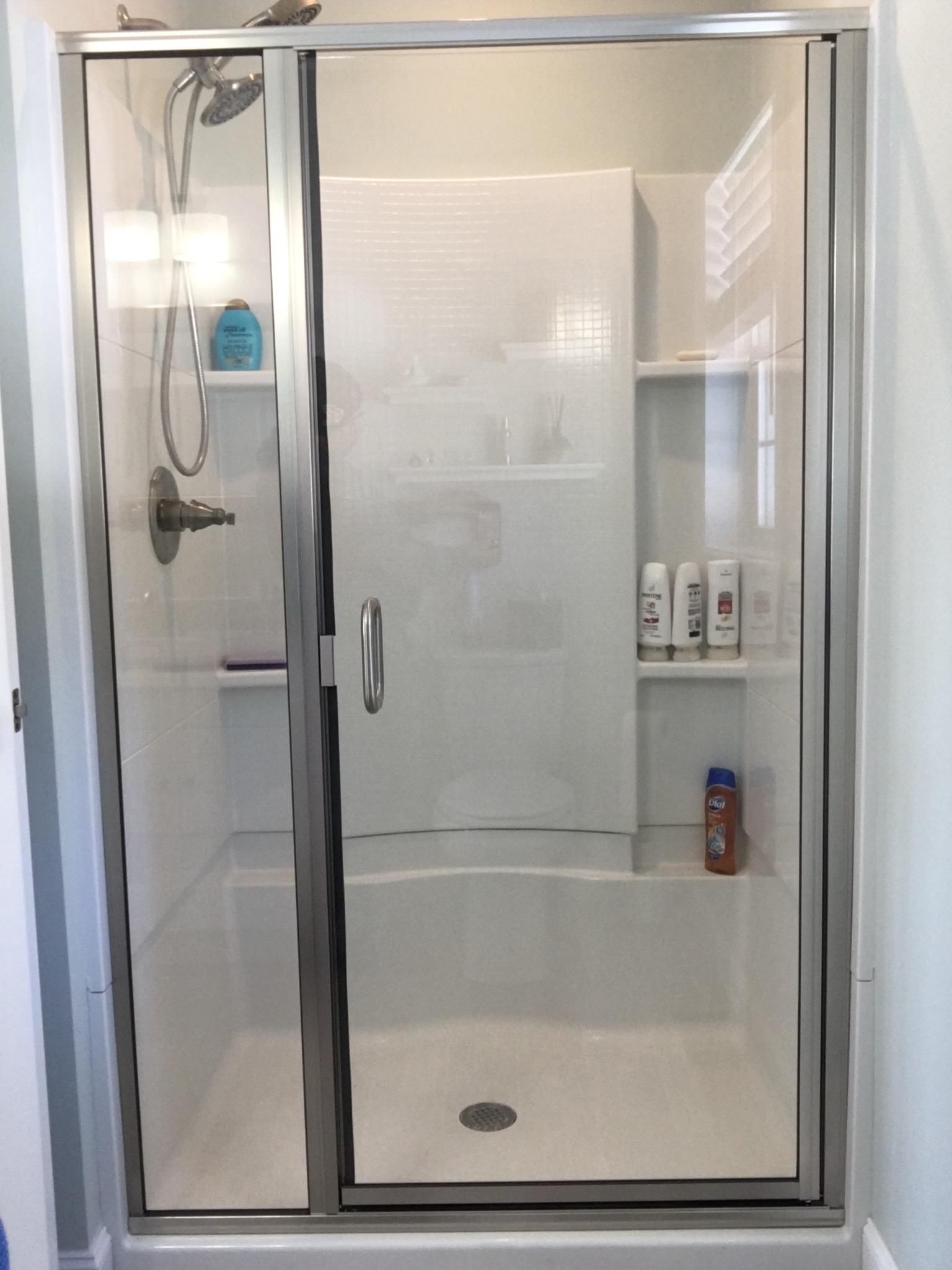 A shower stall with a glass door and a shower head in a bathroom.