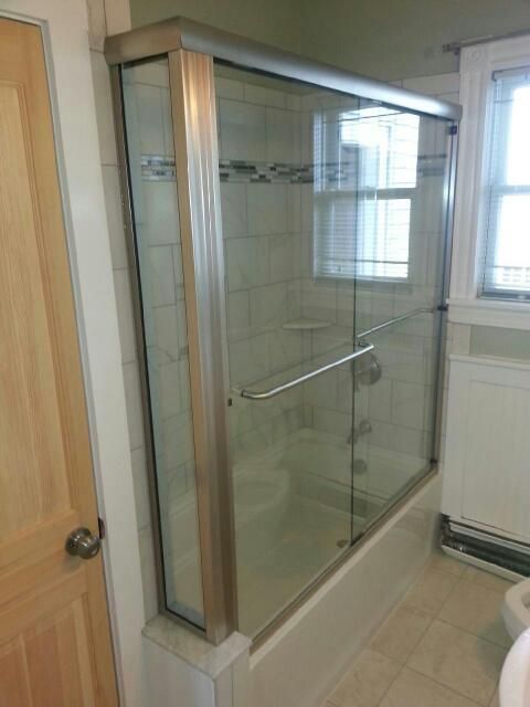 A bathroom with a bathtub and a glass shower door.