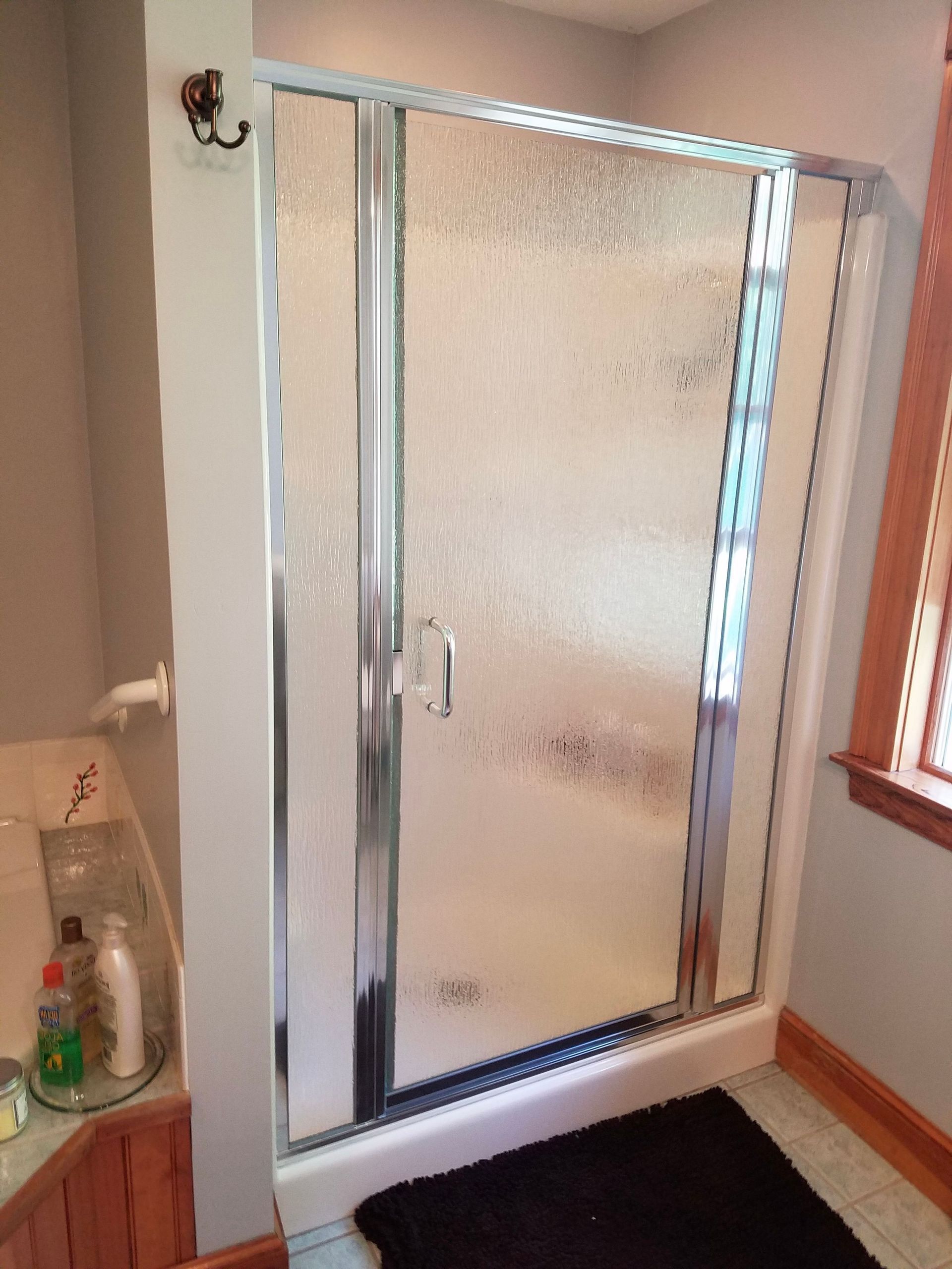 A bathroom with a walk in shower and a window