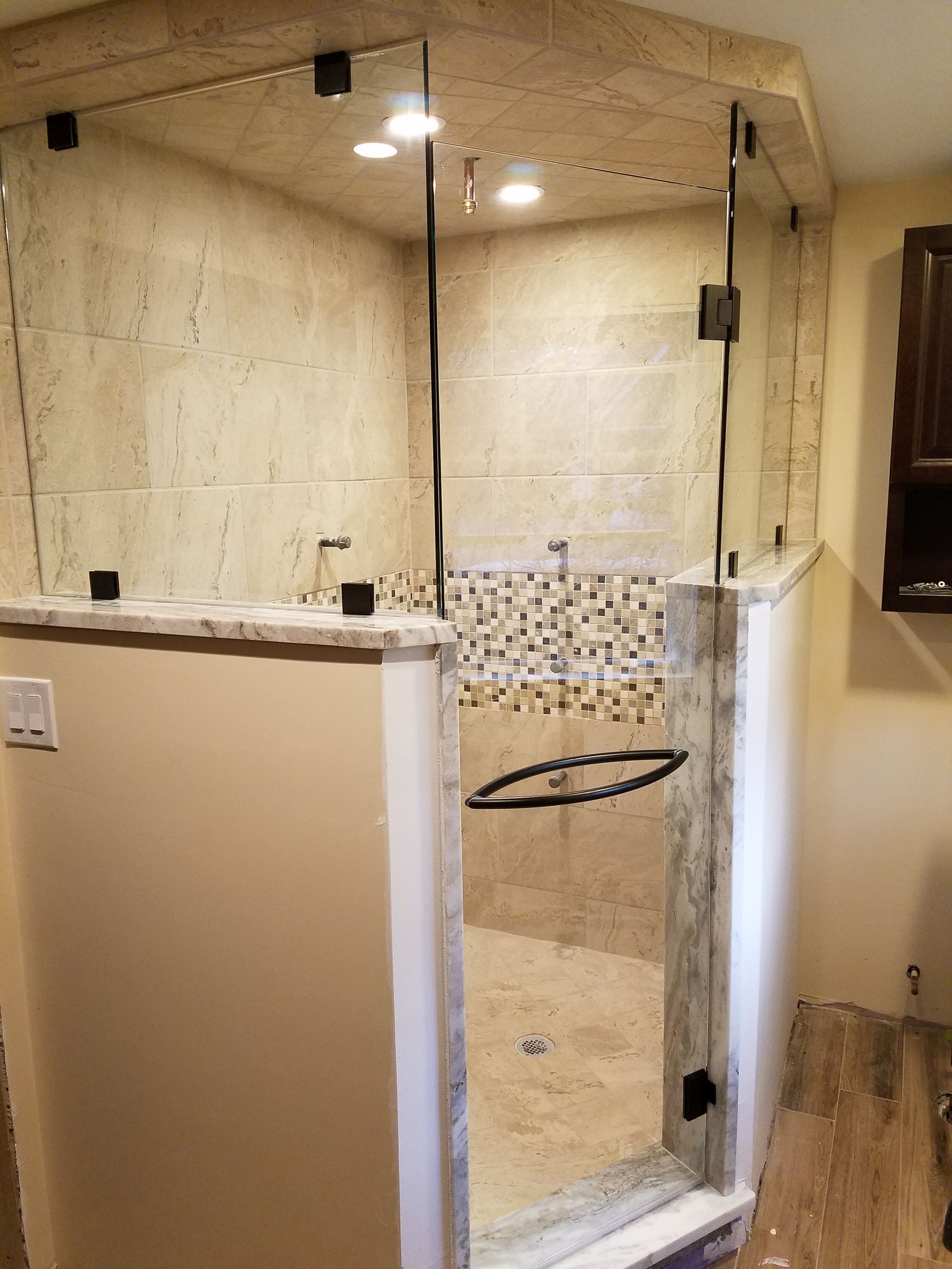 A bathroom with a walk in shower with a glass door.