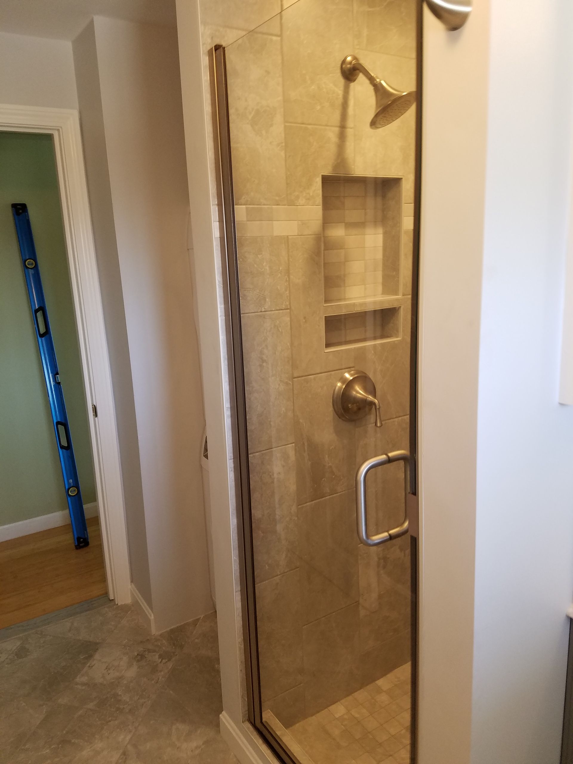 A bathroom with a shower and a blue level on the wall.