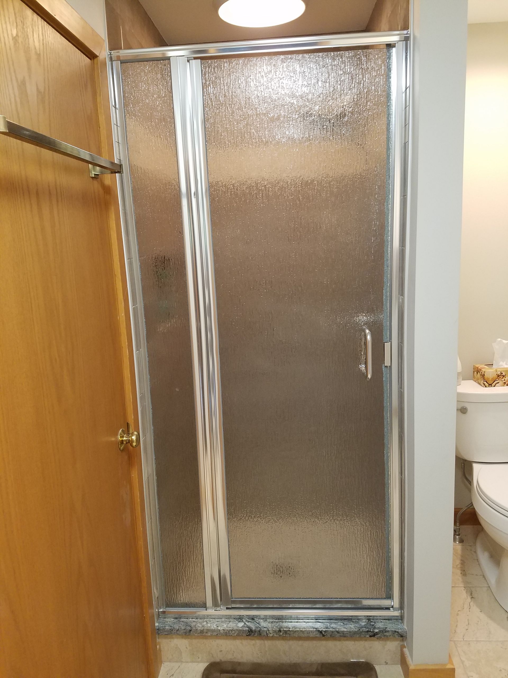 A shower stall in a bathroom next to a toilet.