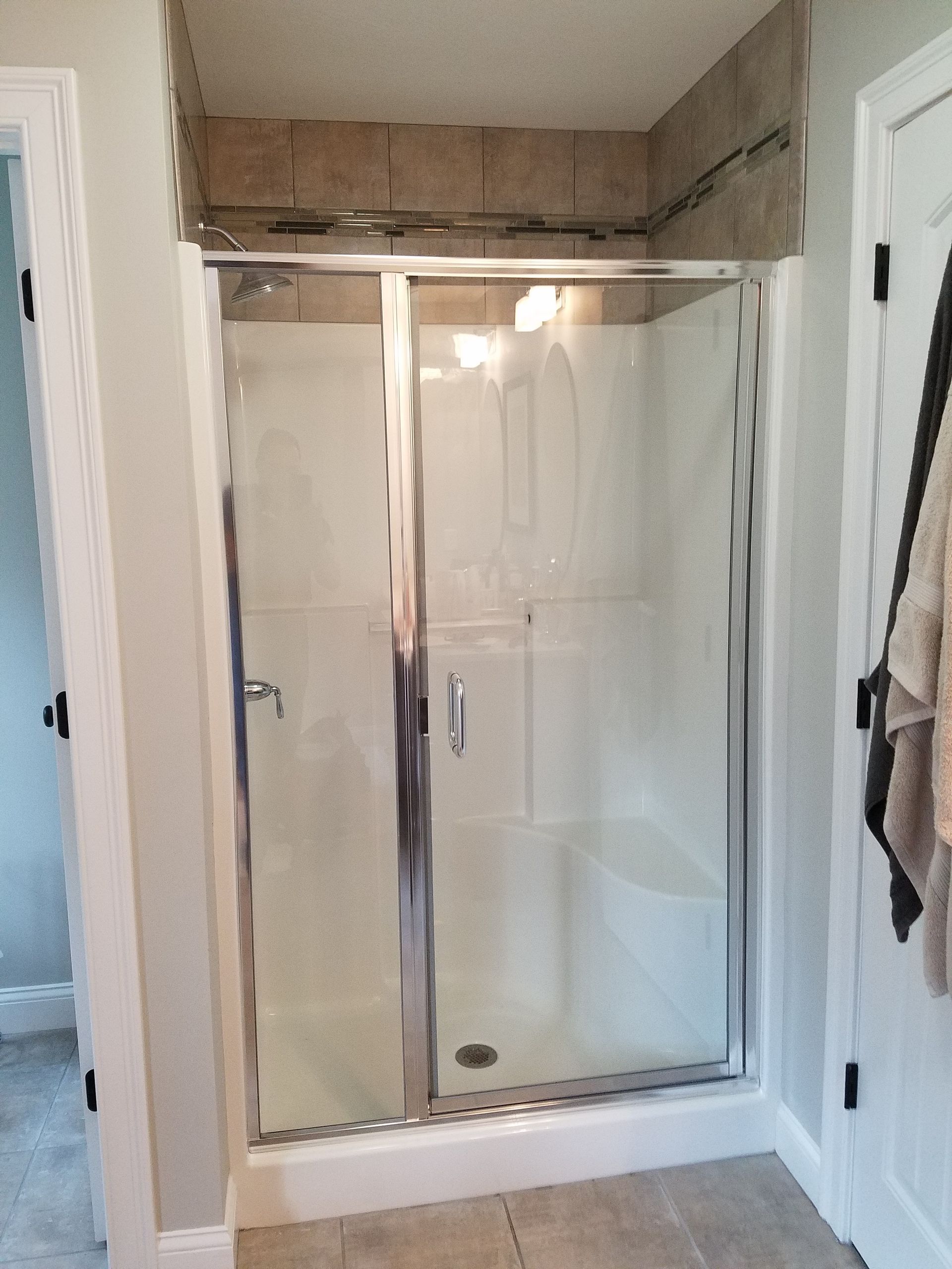 A bathroom with a walk in shower with a glass door