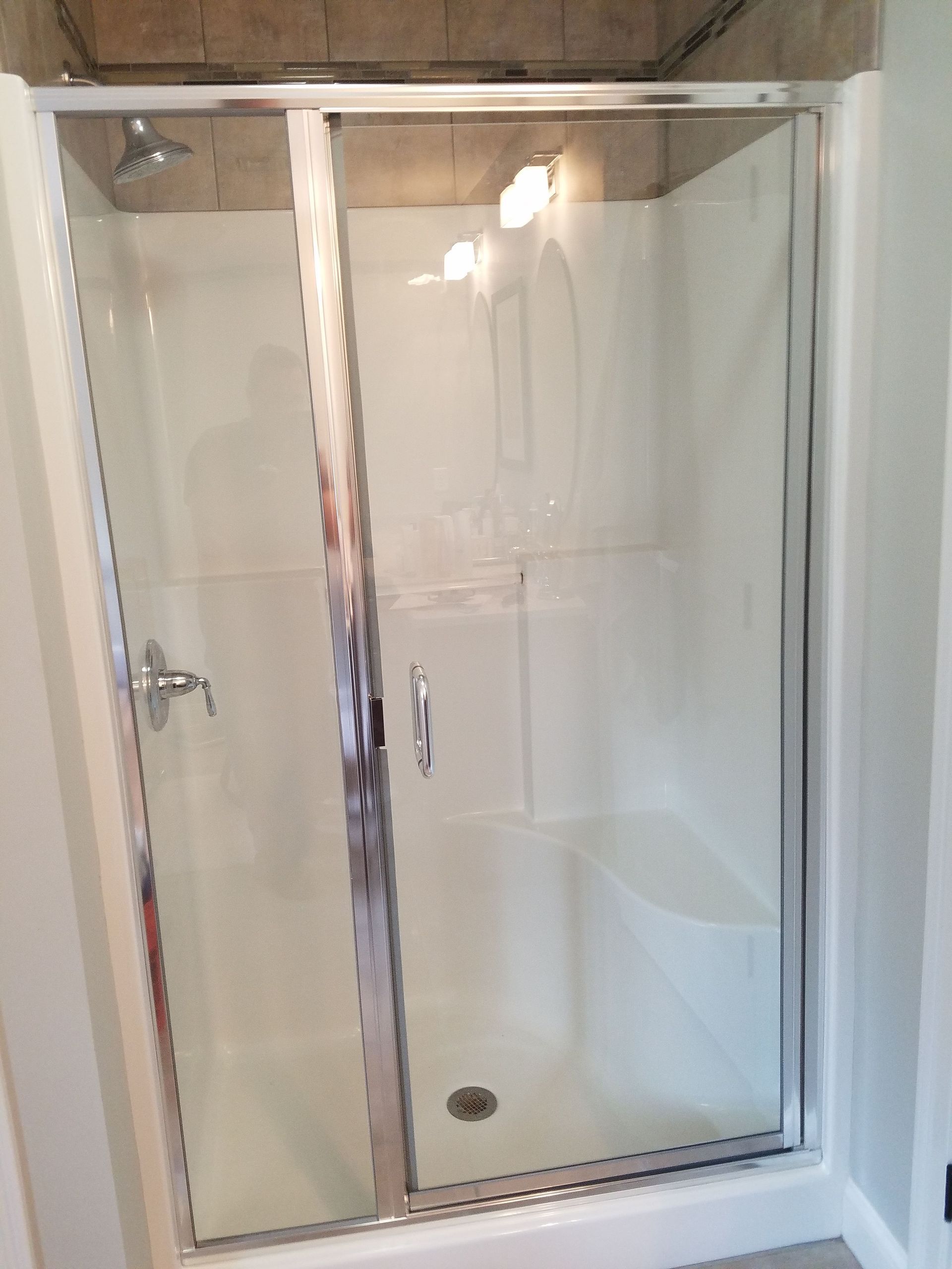 A shower stall with a glass door and a shower head in a bathroom.