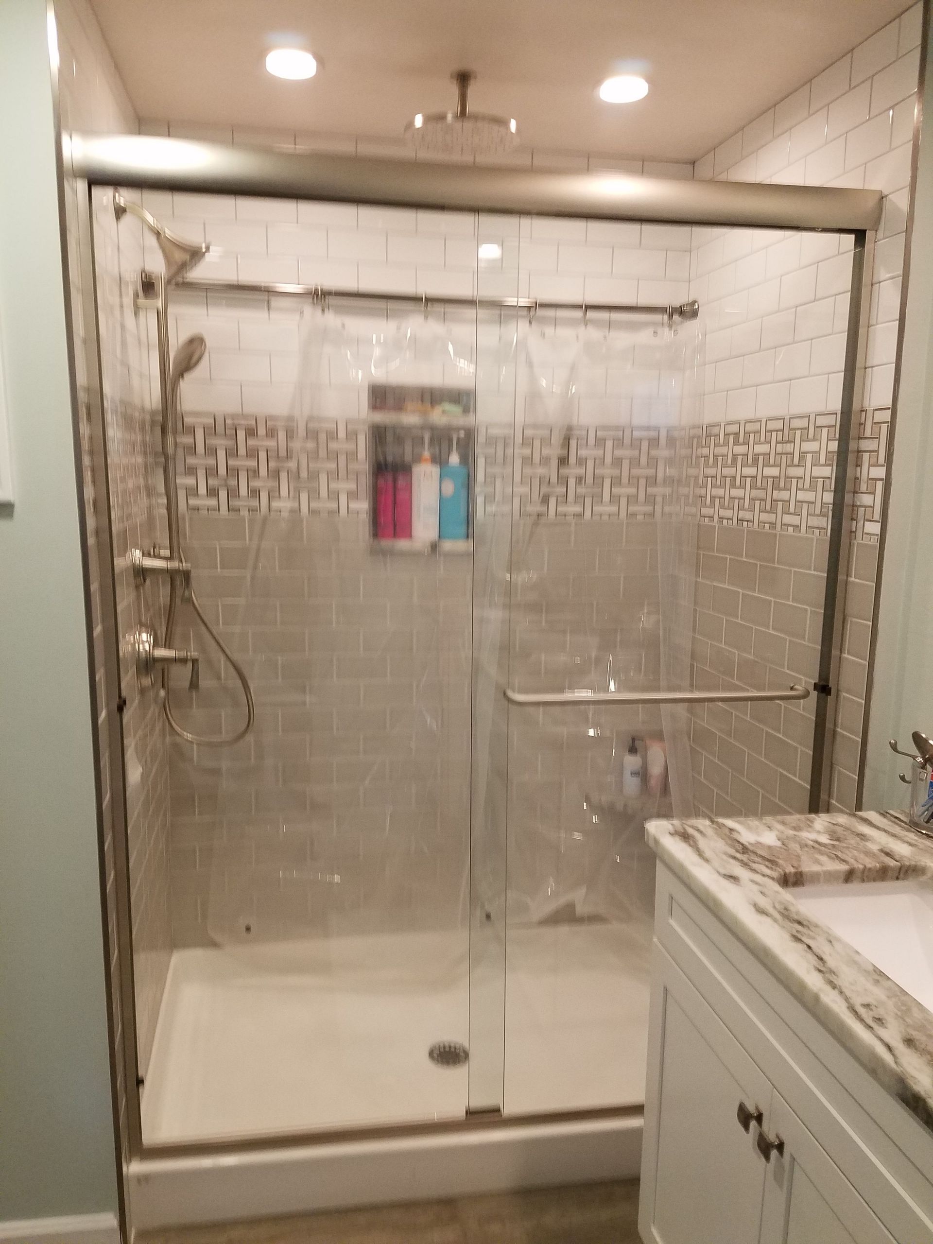 A bathroom with a sliding glass shower door and a sink