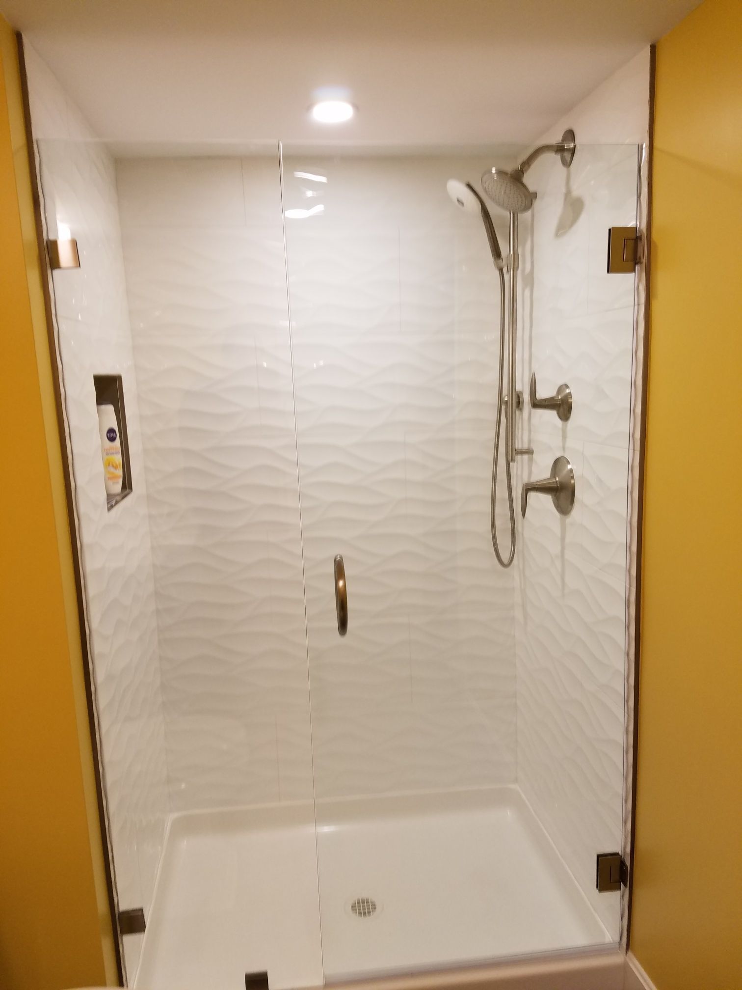 A shower with a glass door and a shower head.