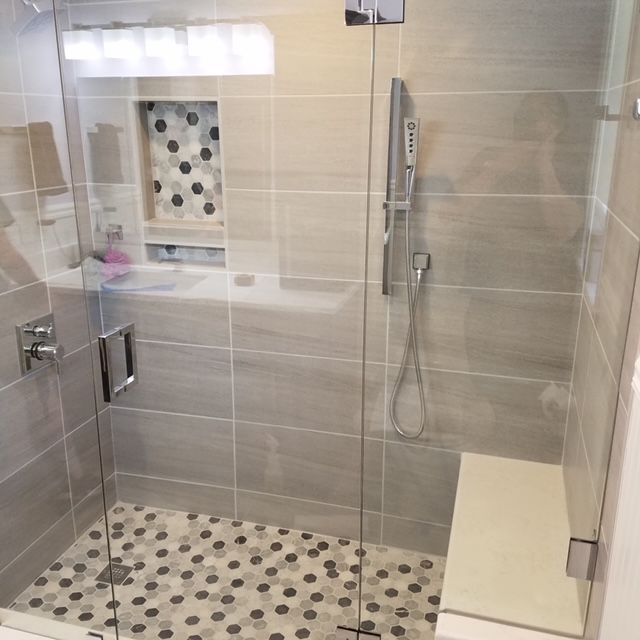 A bathroom with a walk in shower with a glass door