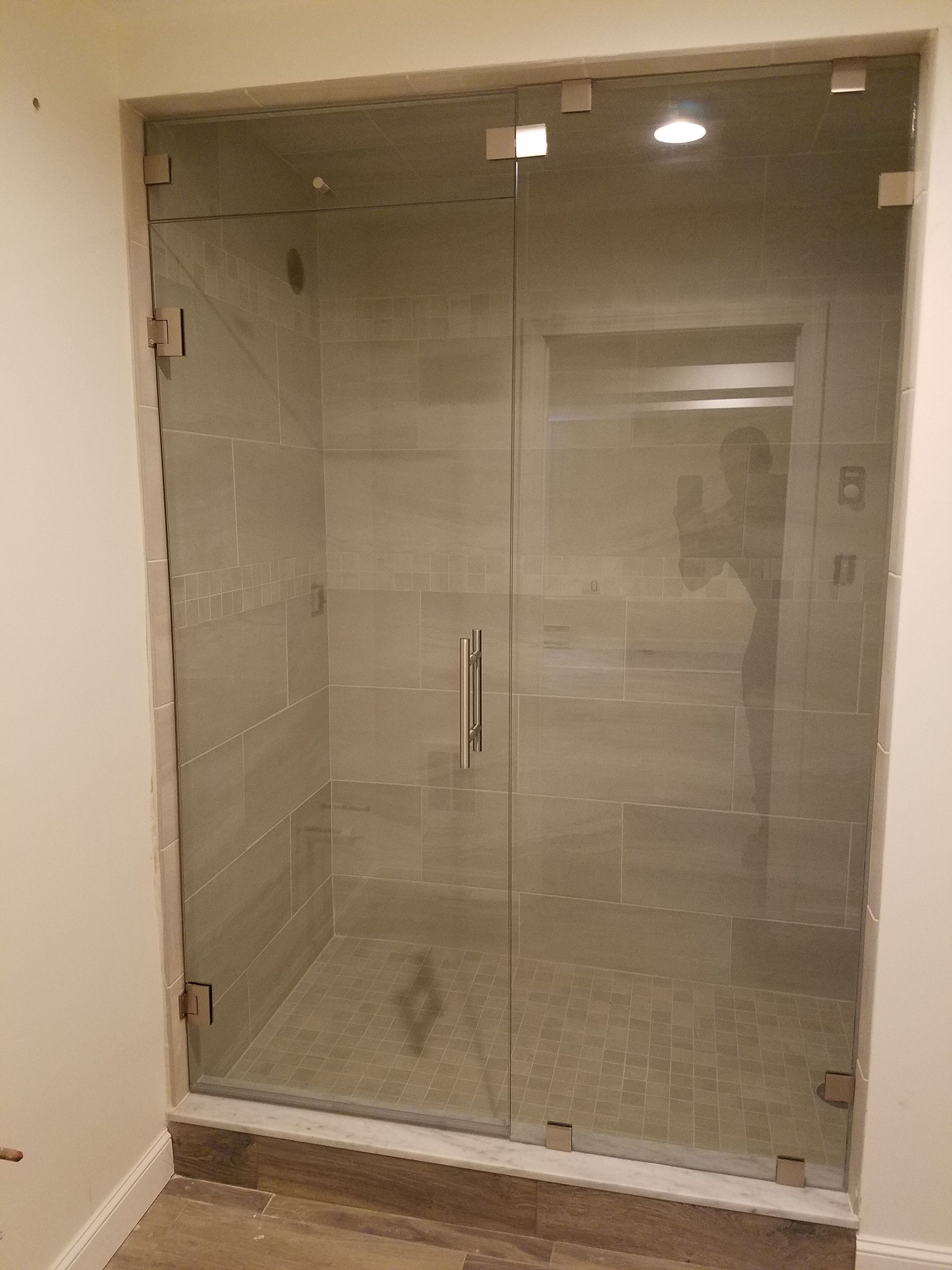A bathroom with a walk in shower with a glass door.