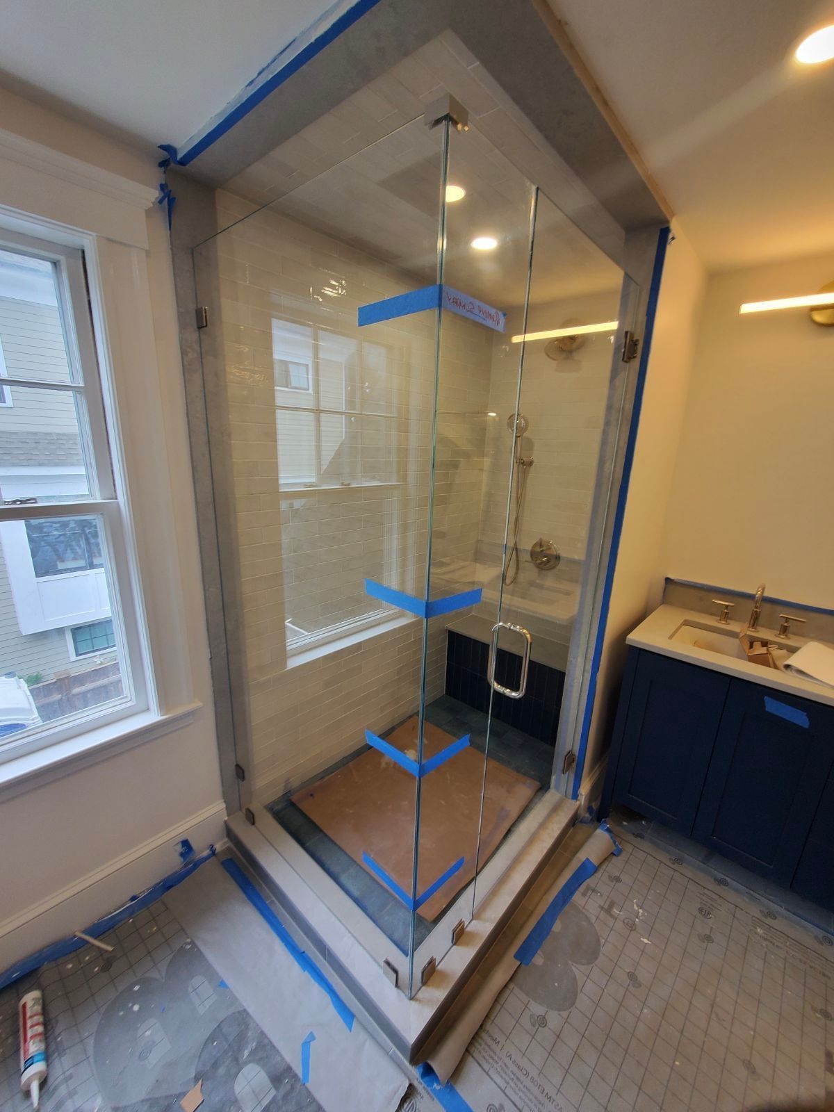 A bathroom with a glass shower and a window