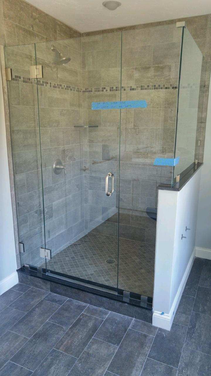 A bathroom with a walk in shower with a glass door.